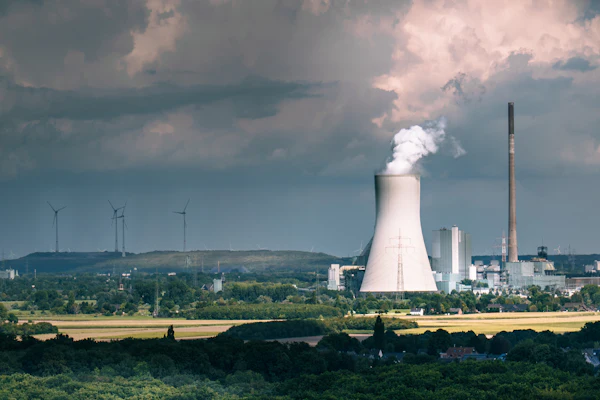 Menara pendingin industri mengeluarkan uap, menggambarkan sistem boiler