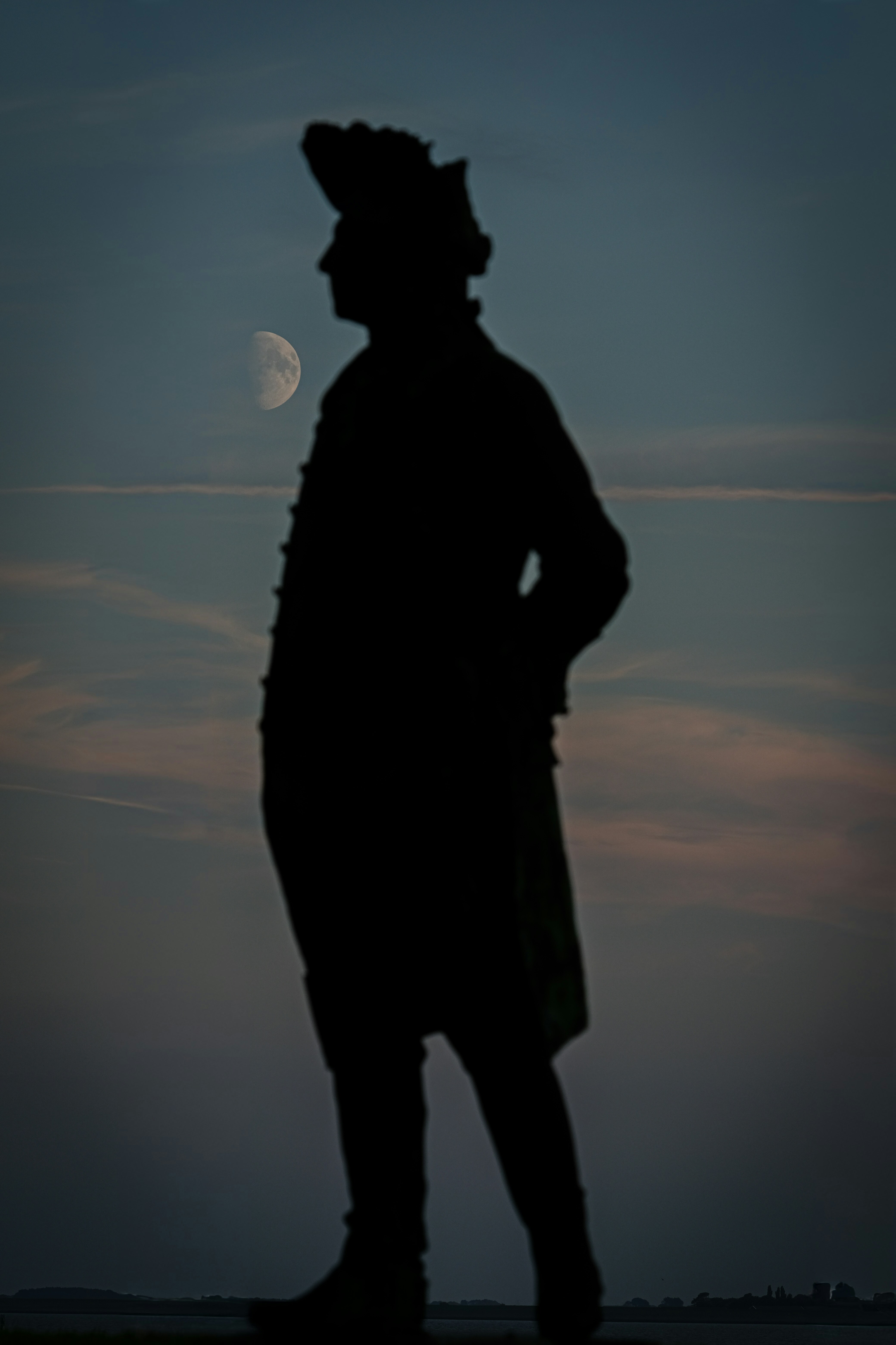 Silhouette of a man against a twilight sky with moon.