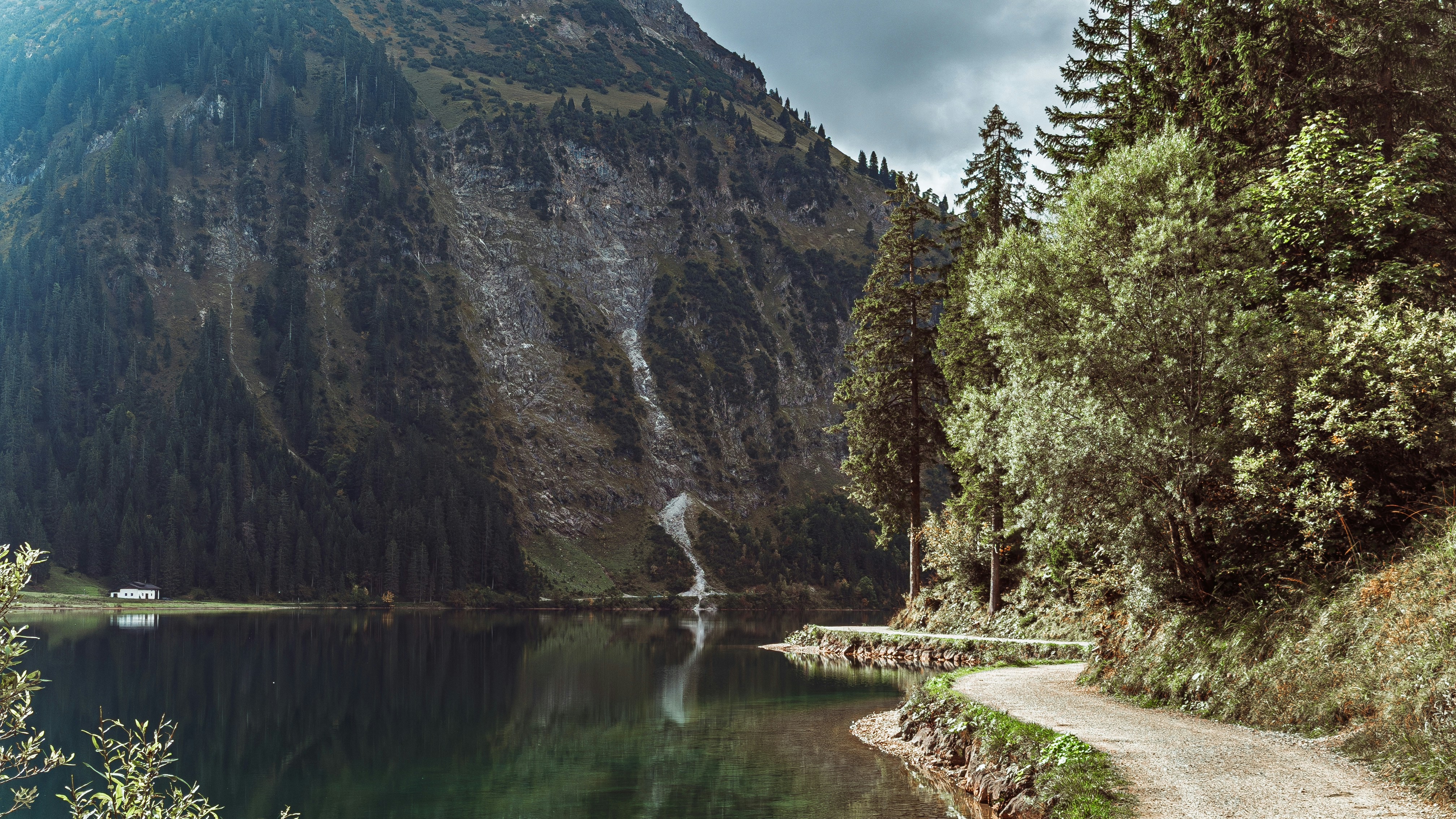 Mountain lake with a winding dirt road and trees.