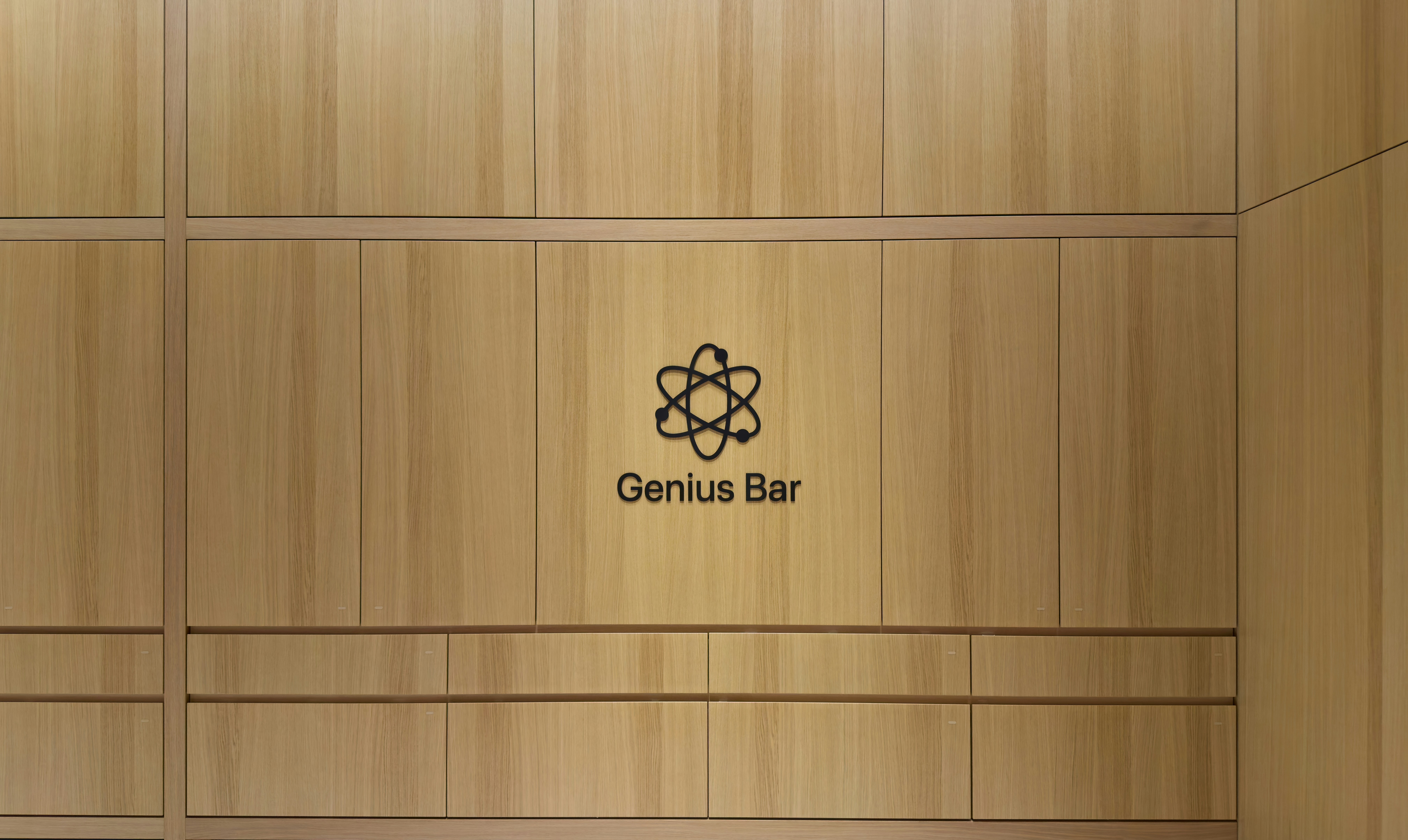 A minimalist shot of the Genius Bar inside an Apple Store, featuring the clean wooden wall design and the iconic Genius Bar logo. Captured with a focus on simplicity, geometry, and the modern aesthetic of Apple retail spaces.
