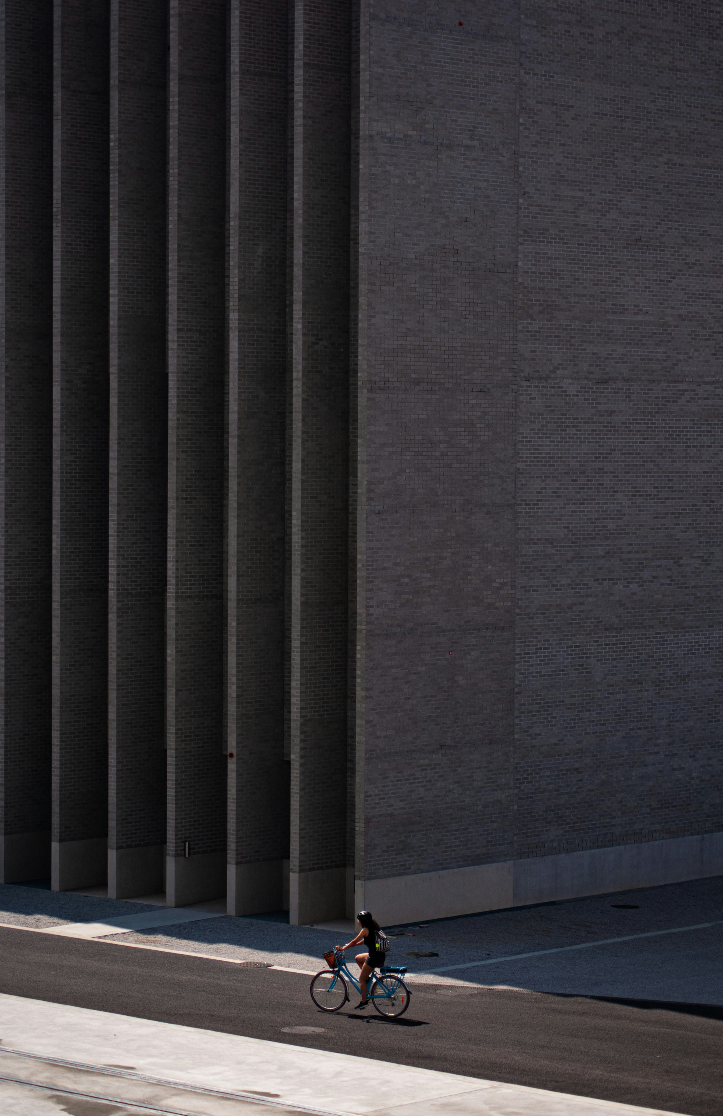 Person rides bicycle past modern building facade