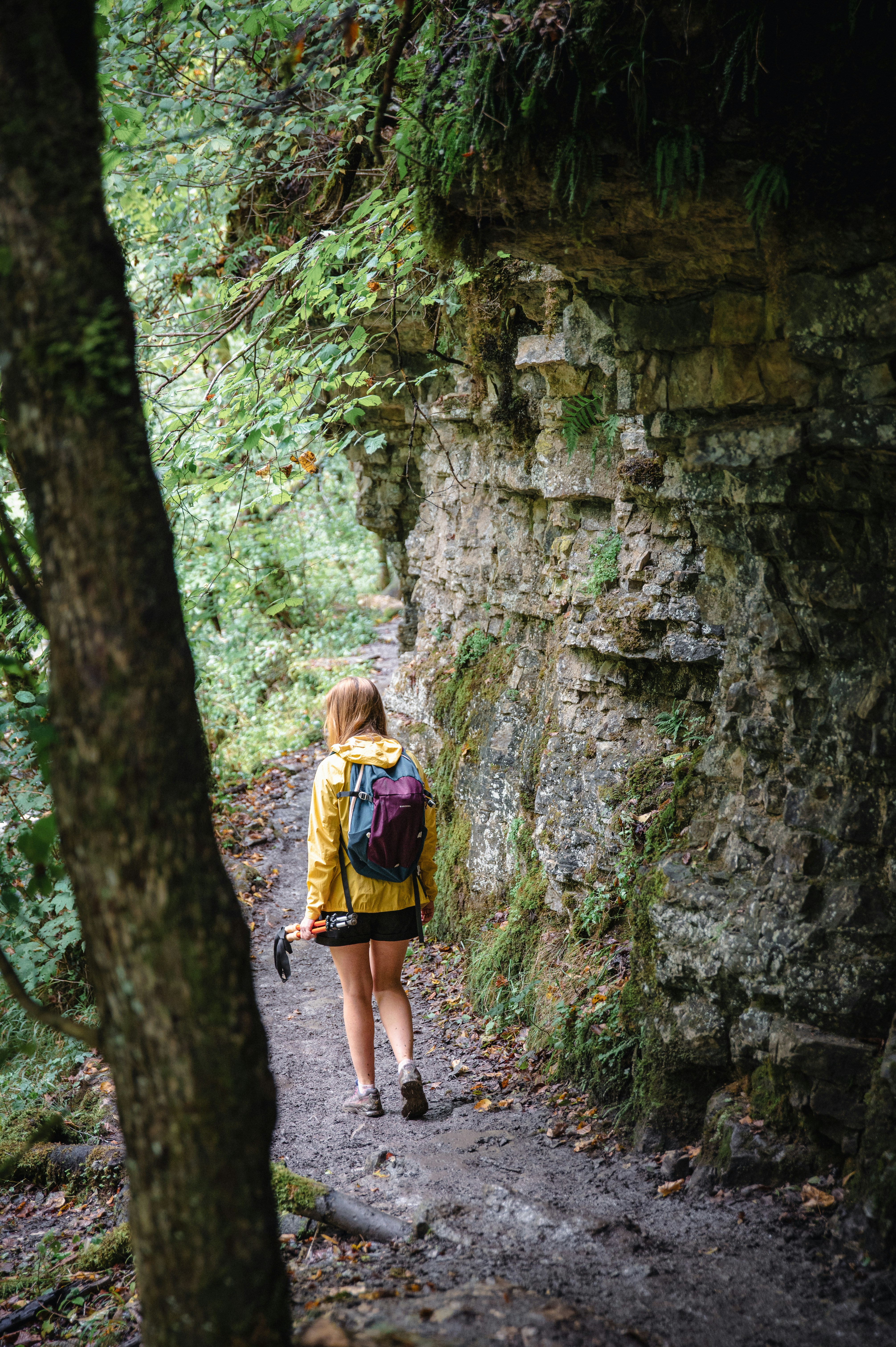 Woman hiking on a forest path near a rock formation