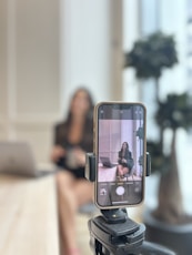 Woman recording herself on smartphone in office.