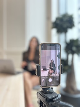 Woman recording herself on smartphone in office.