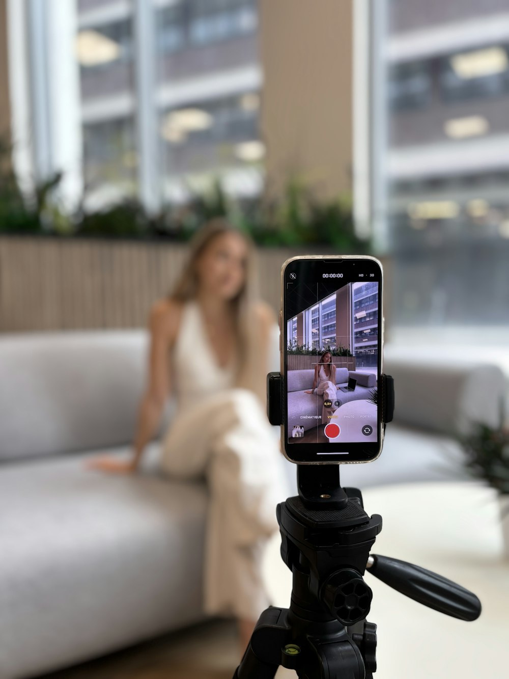 Woman recording video content on a smartphone tripod