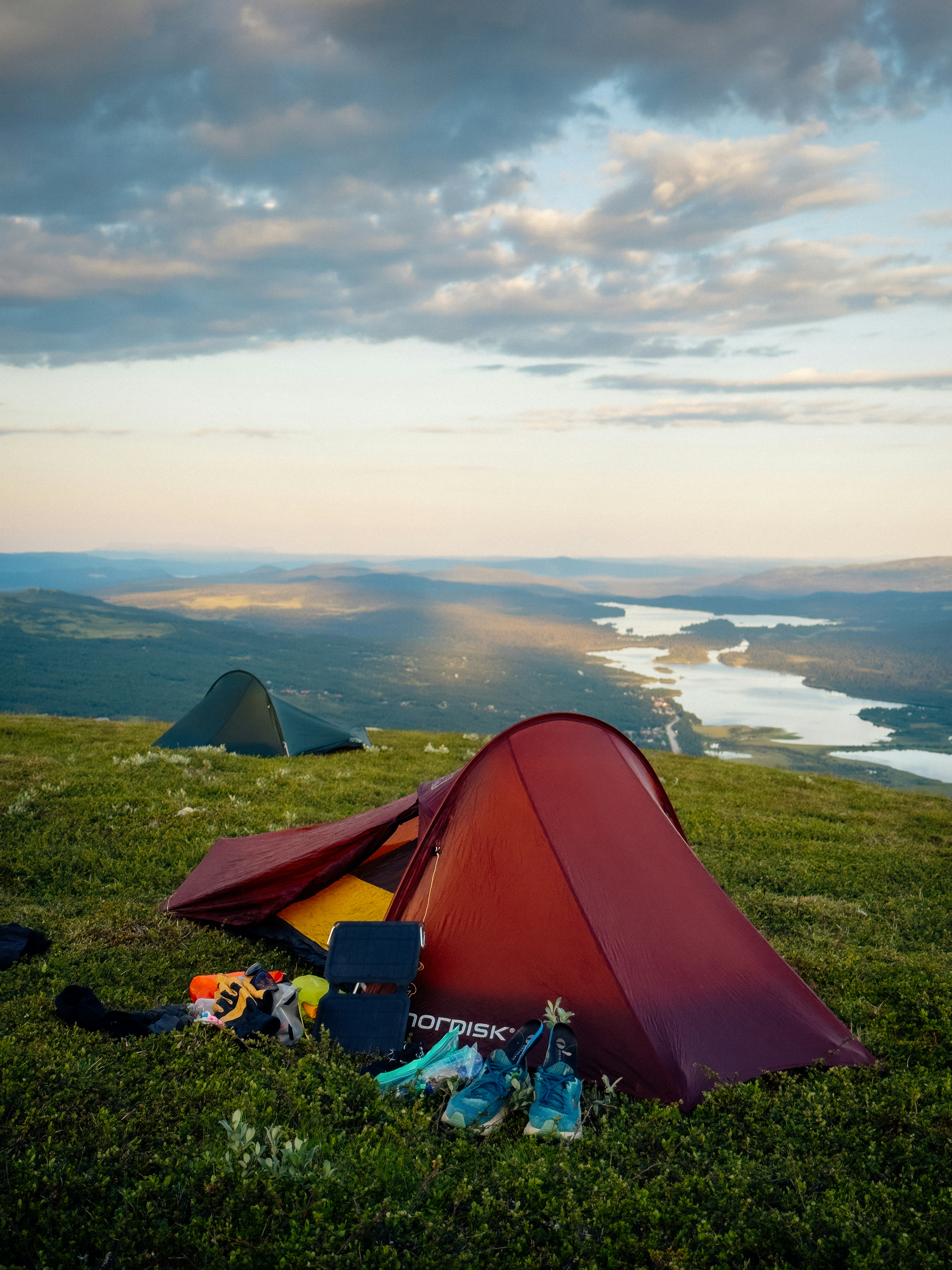 Two tents on a grassy hill overlooking a lake