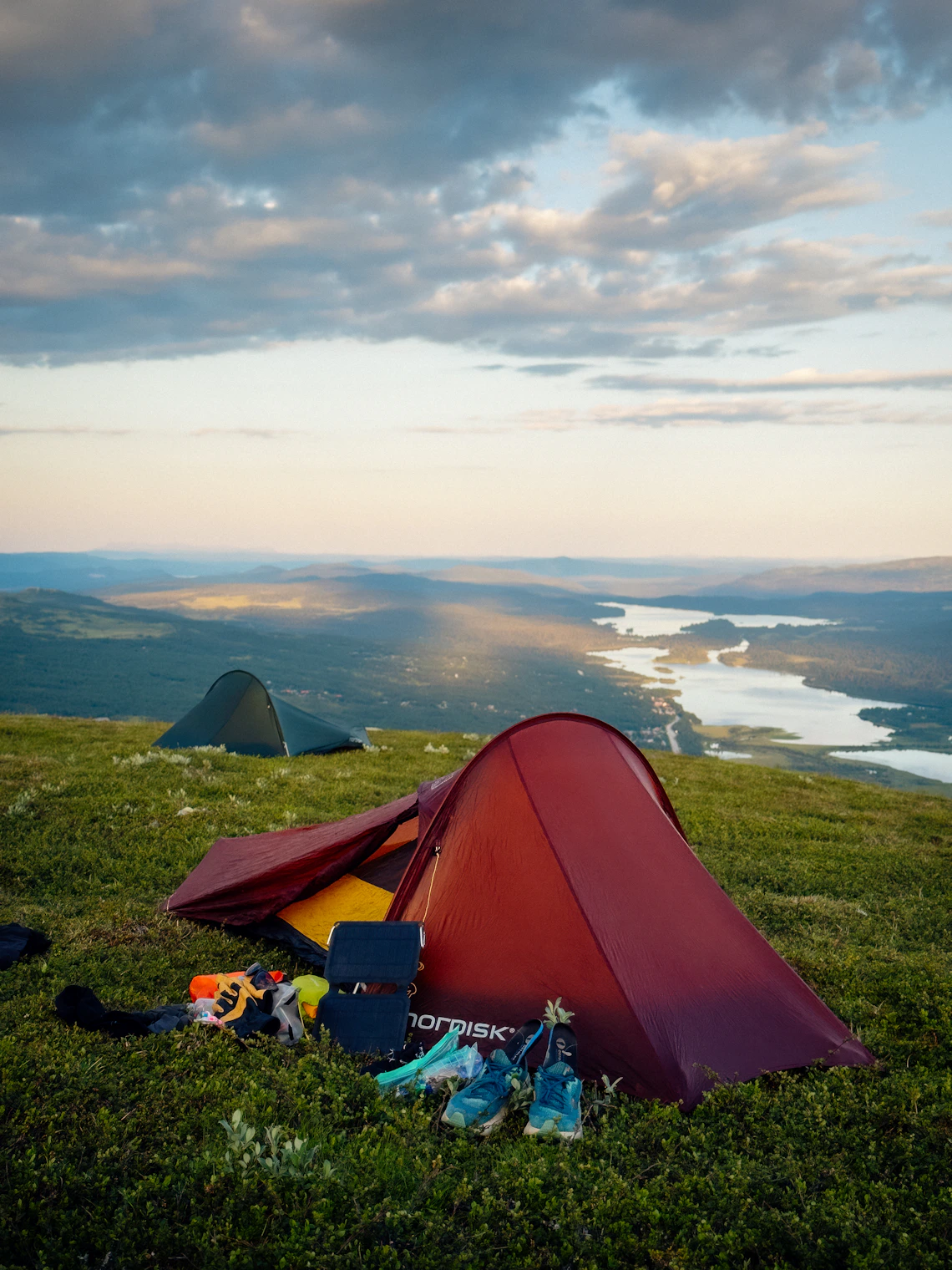 Camping tents on a grassy landscape overlooking a lake
