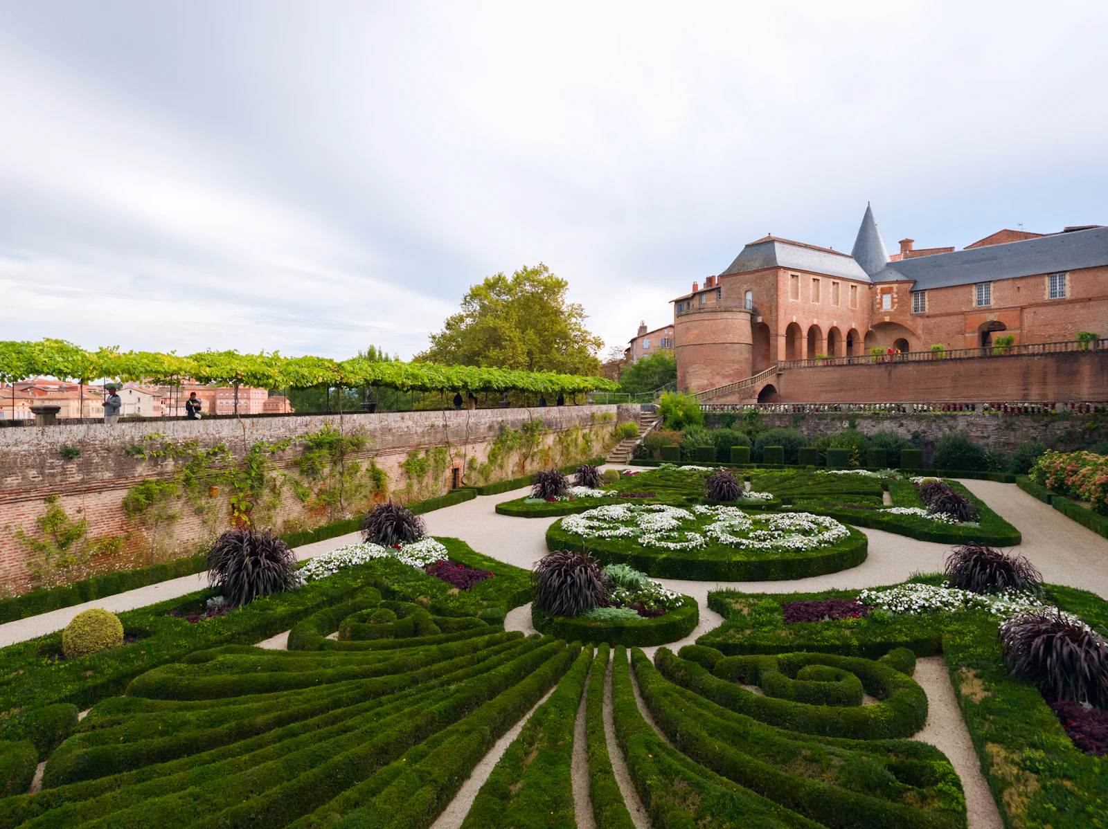 A formal parterre garden seen from above, edged in clipped boxwood