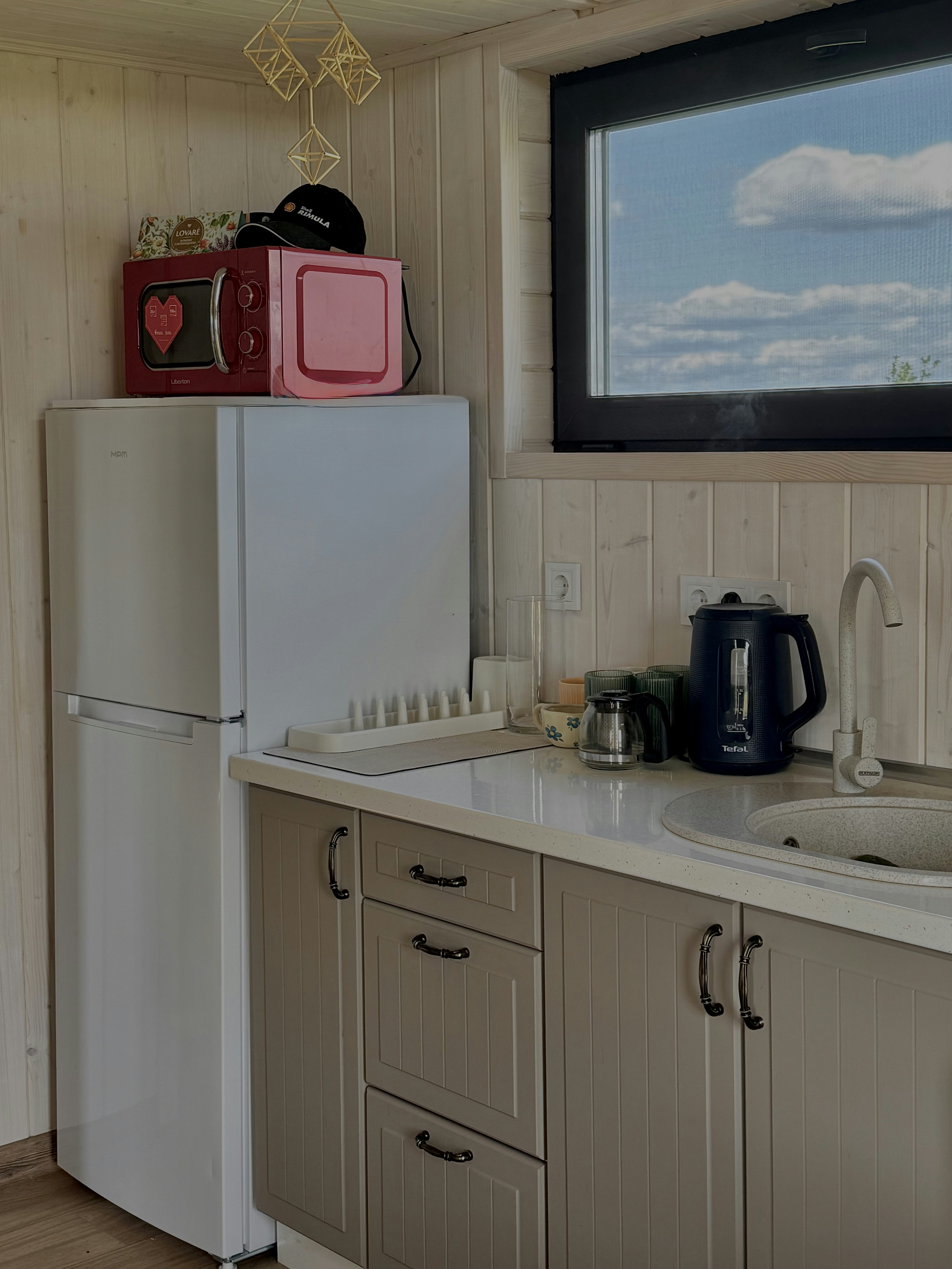 Compact kitchen with refrigerator, microwave, and sink.