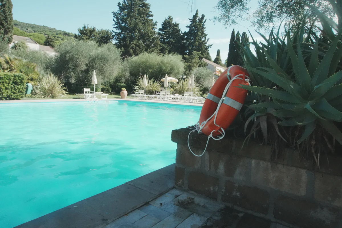 Two orange life preservers by a swimming pool.