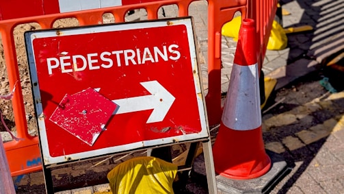 Red sign with white text 'pedestrians' and arrow.