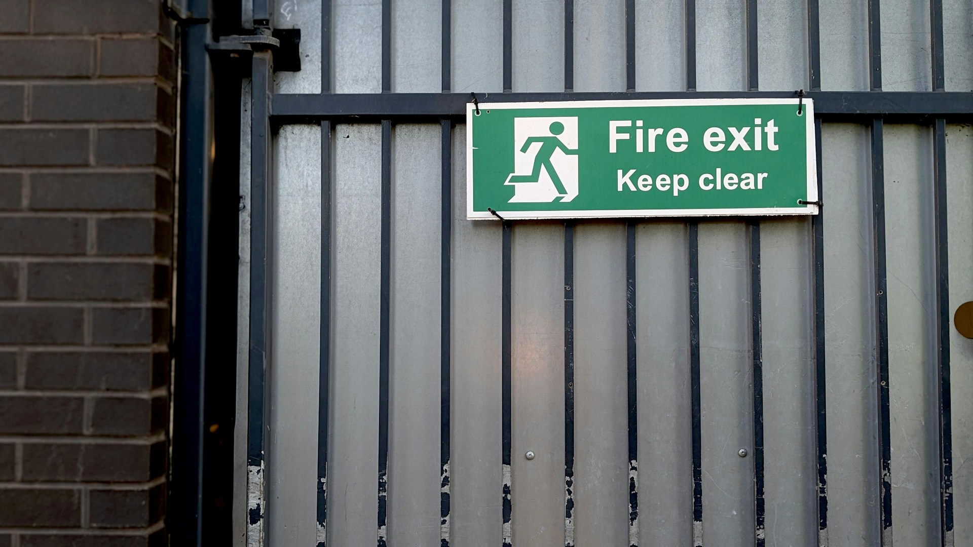 Green fire exit sign on metal gate