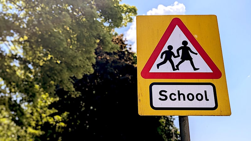 A yellow school crossing warning sign with children silhouettes near a Las Vegas school zone