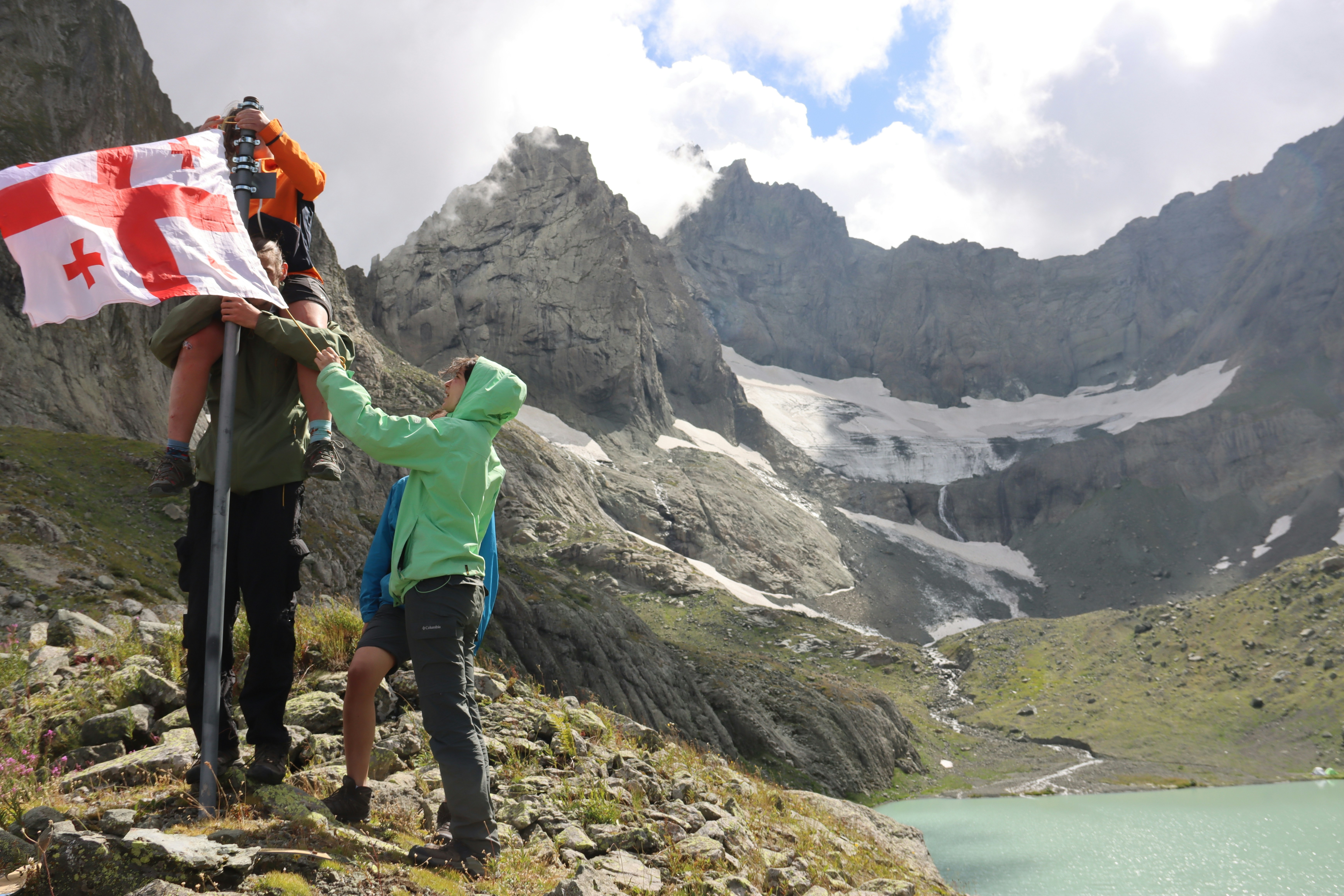 Hikers plant georgian flag on mountain peak