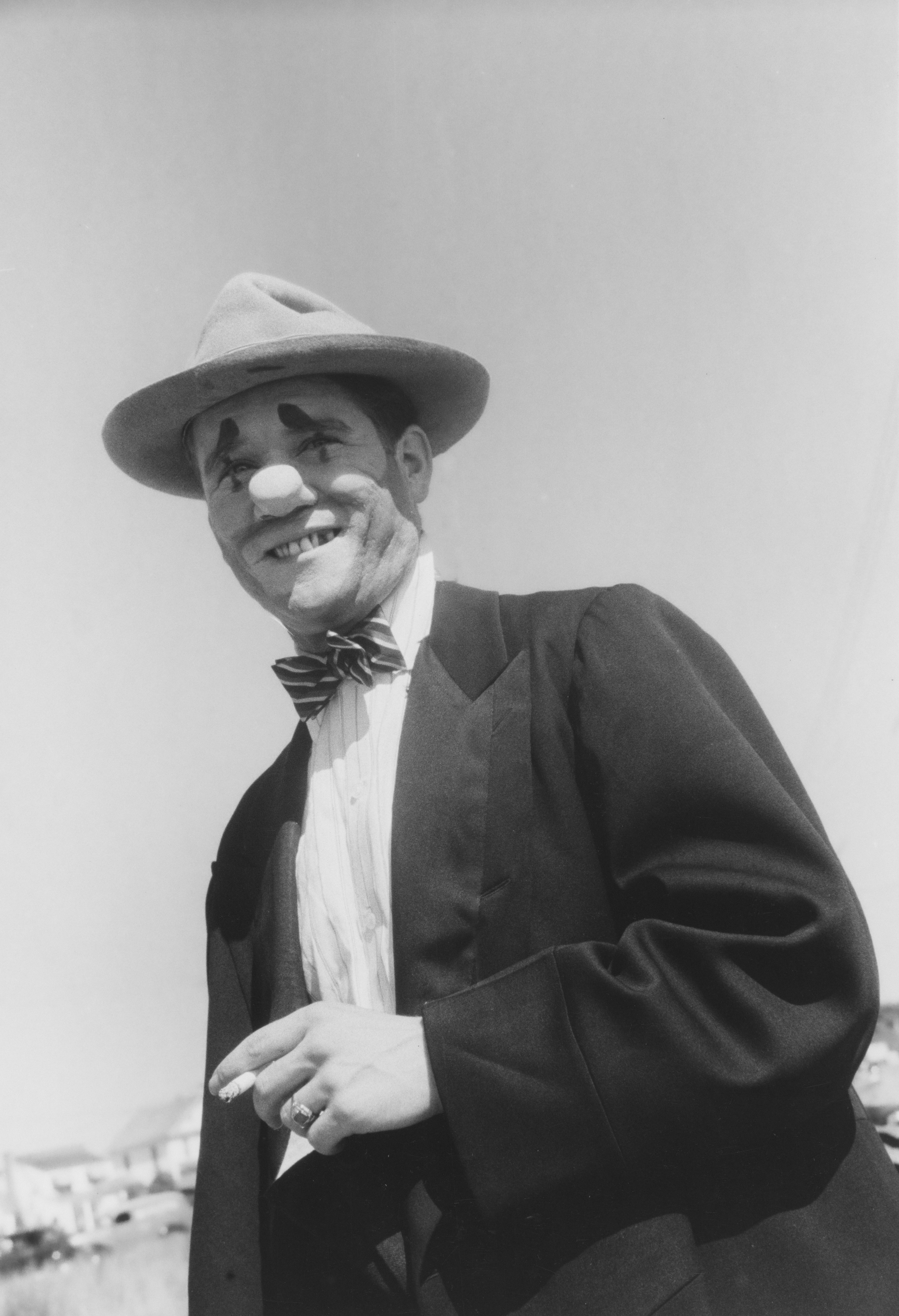 A man in clown makeup wearing a suit and hat.