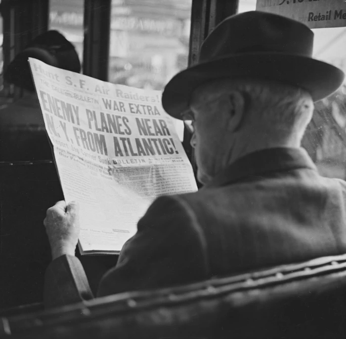 Homem lendo jornal com manchete de guerra