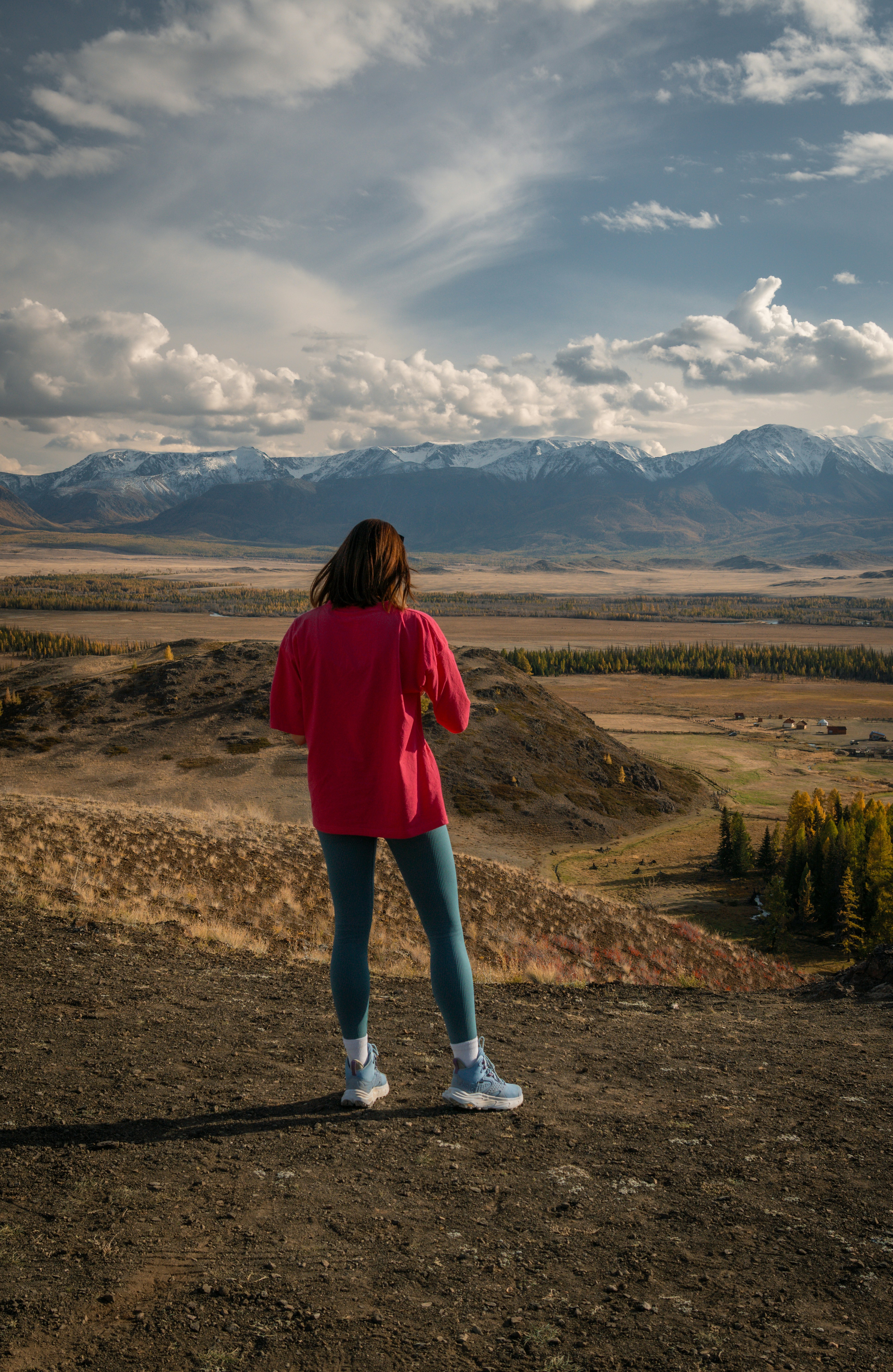 Woman looking at snow-capped mountains in a valley.