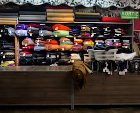 Rolls of colorful fabric displayed on shelves in a store.
