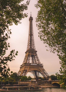Eiffel tower framed by green trees and river