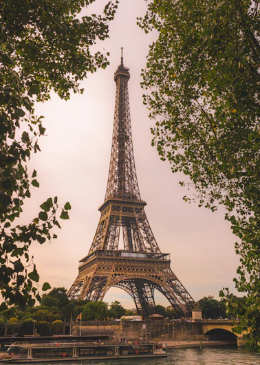 Eiffel tower framed by green trees and river
