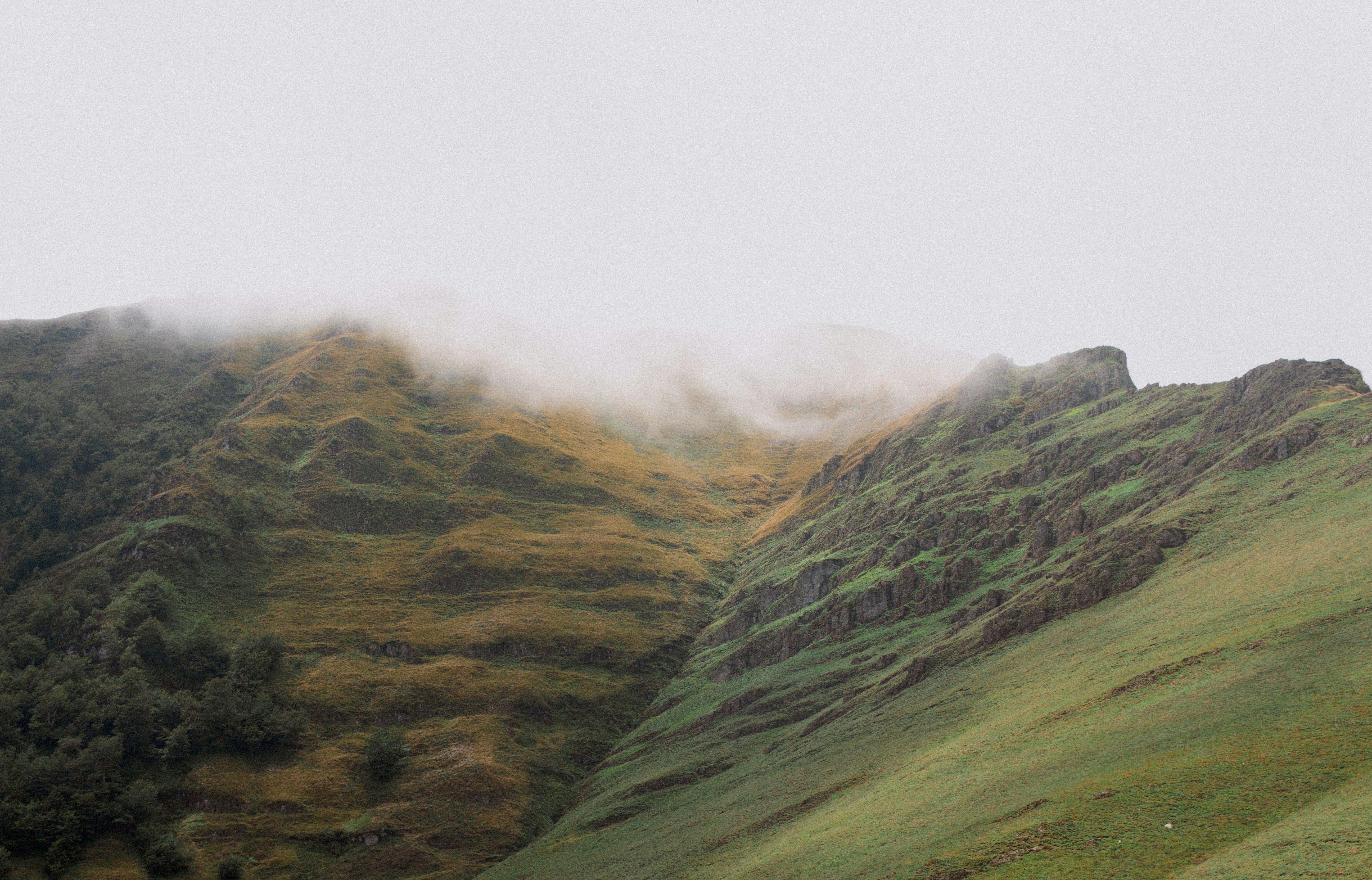 Misty green hills with textured slopes under a bright sky.