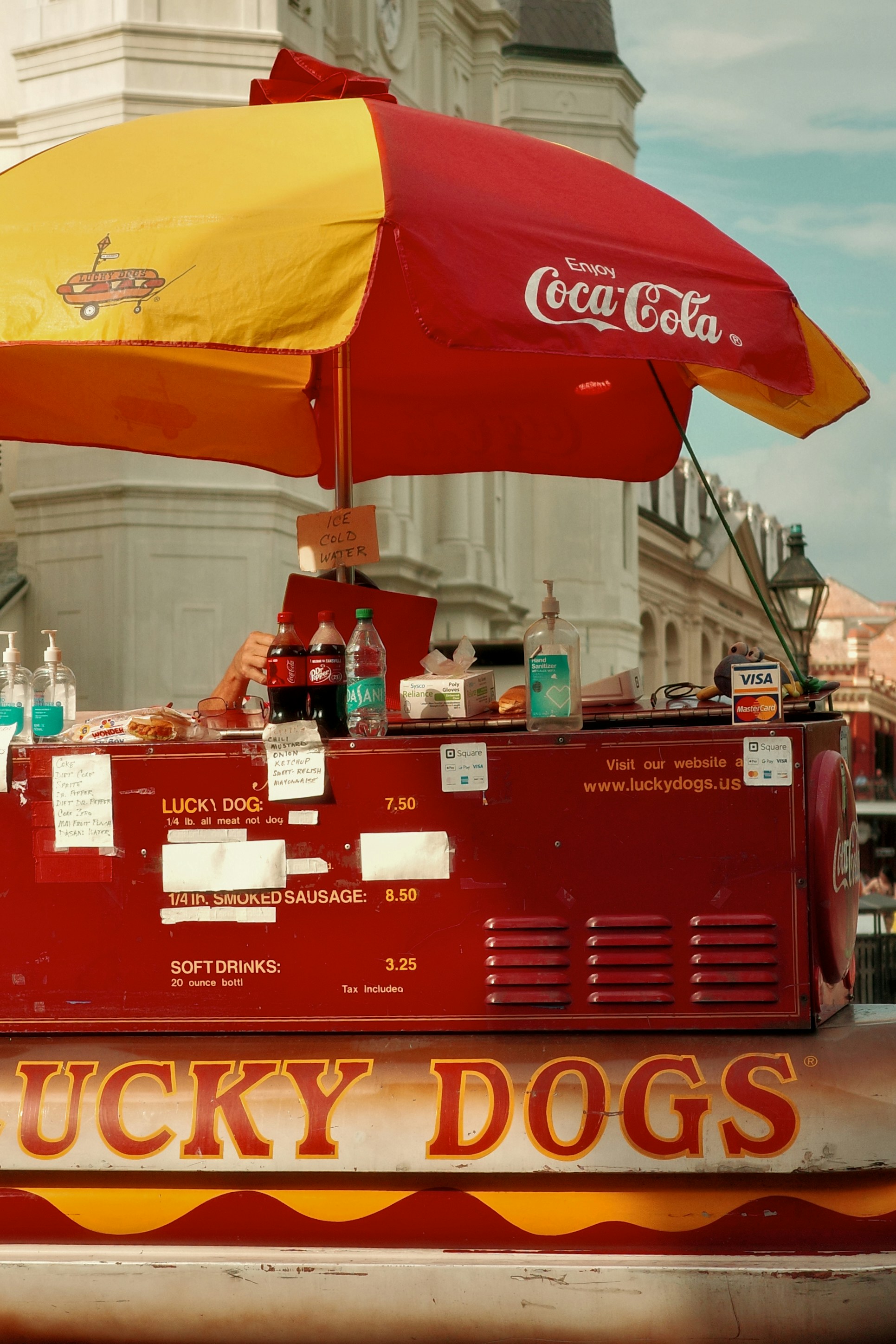 Roter Hot-Dog-Wagen mit gelbem und rotem Regenschirm.