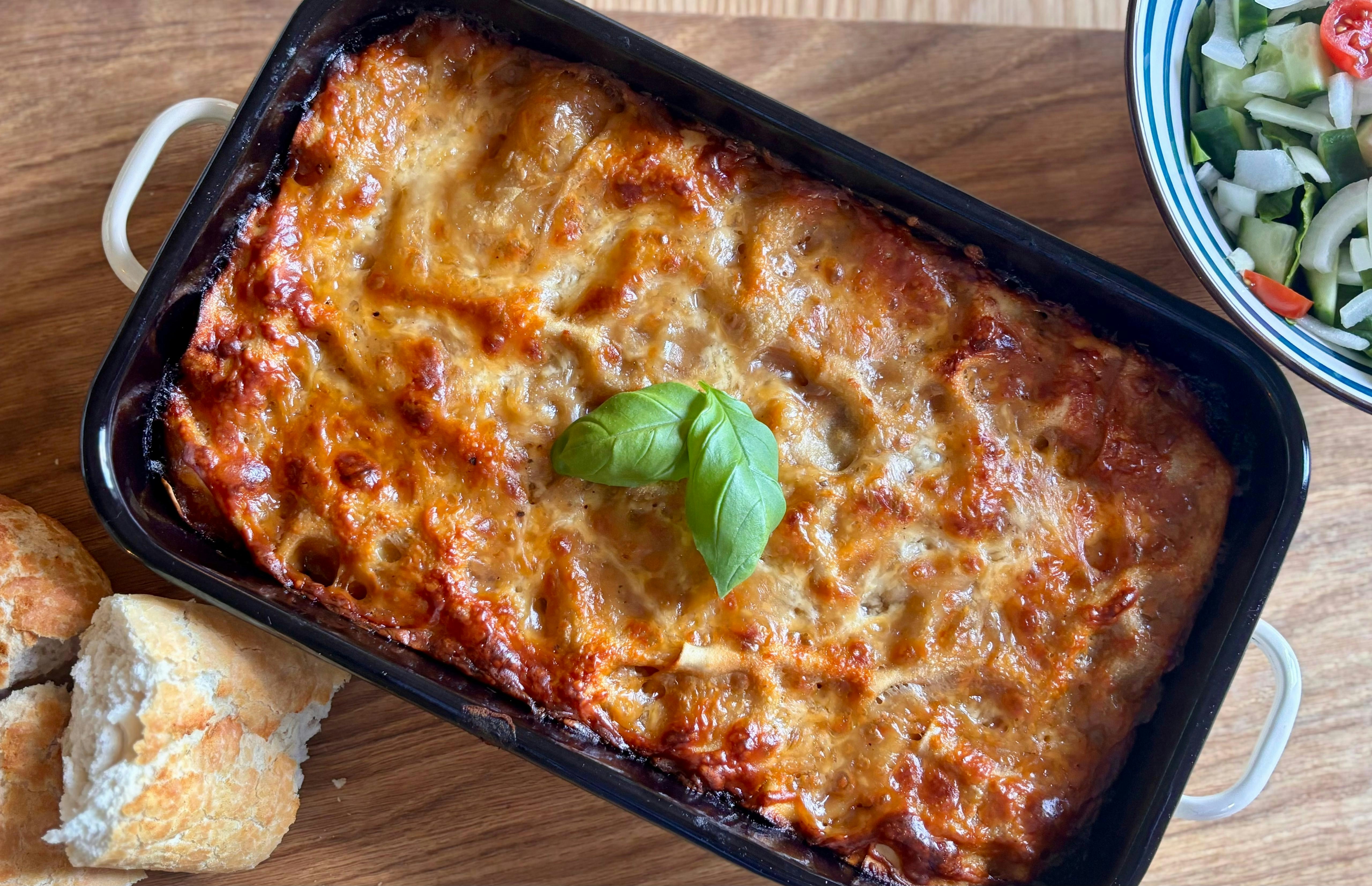 Freshly baked lasagna with a basil leaf garnish.