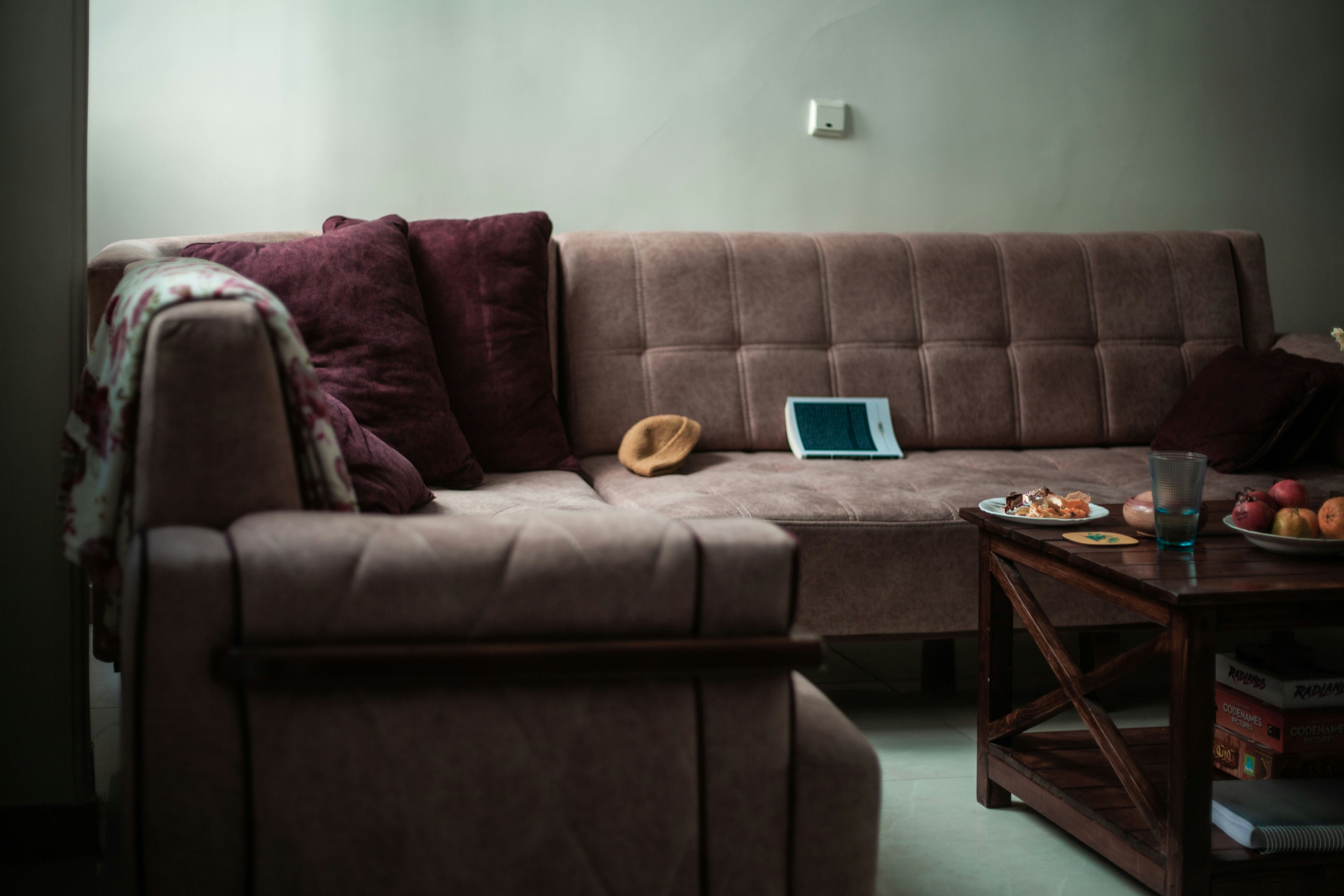 A sectional sofa with pillows and a tablet on it.