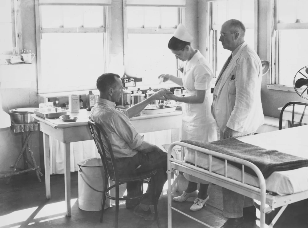 A nurse attending to a patient while a doctor observes, representing coordinated facility care