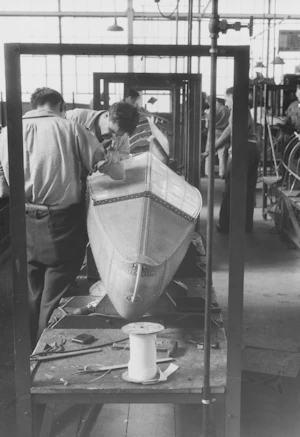 Workers assembling a wooden boat in a workshop