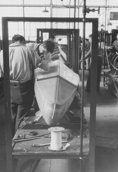 Workers assembling a wooden boat in a workshop