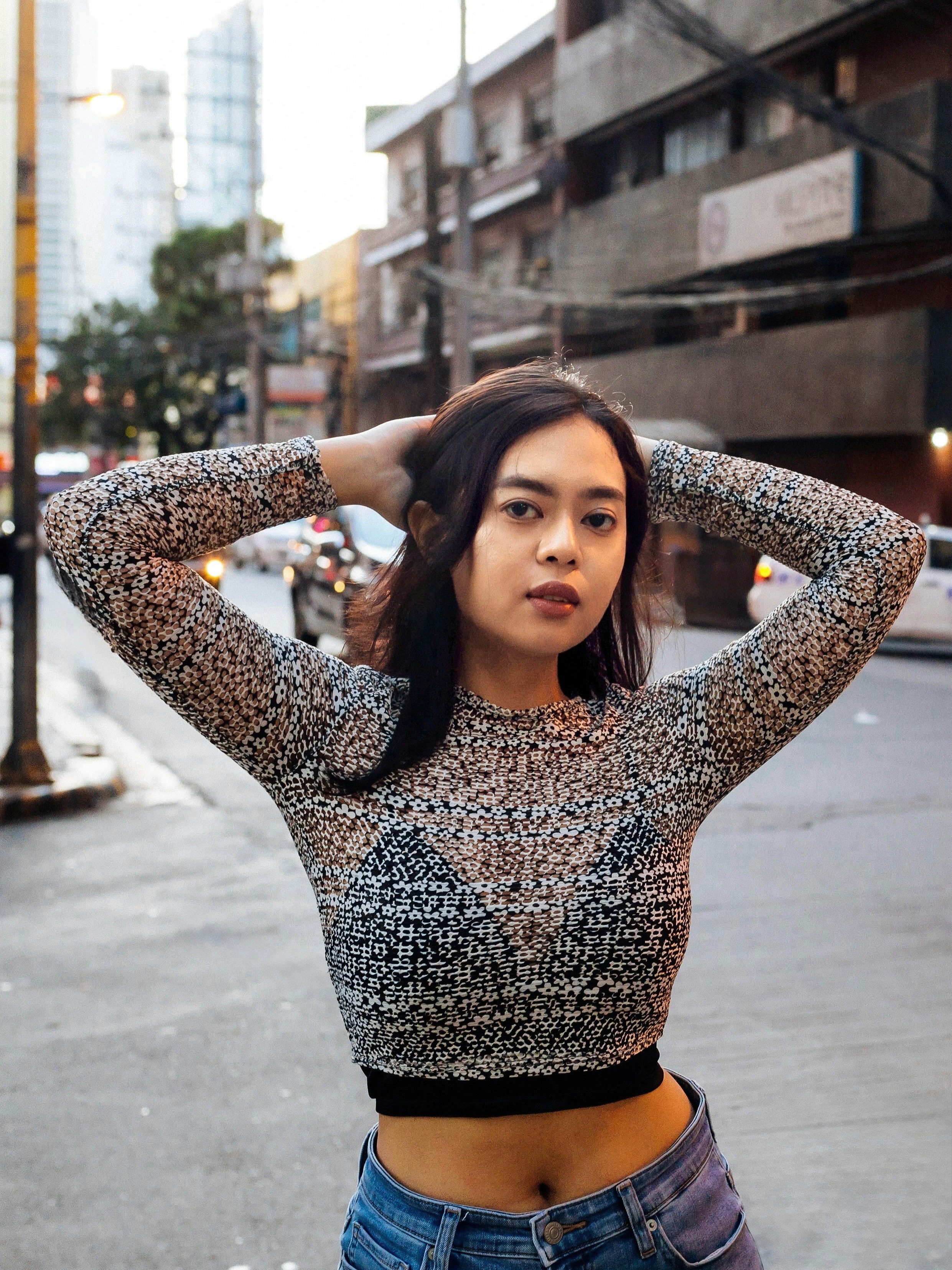 Young woman with hands behind head on city street