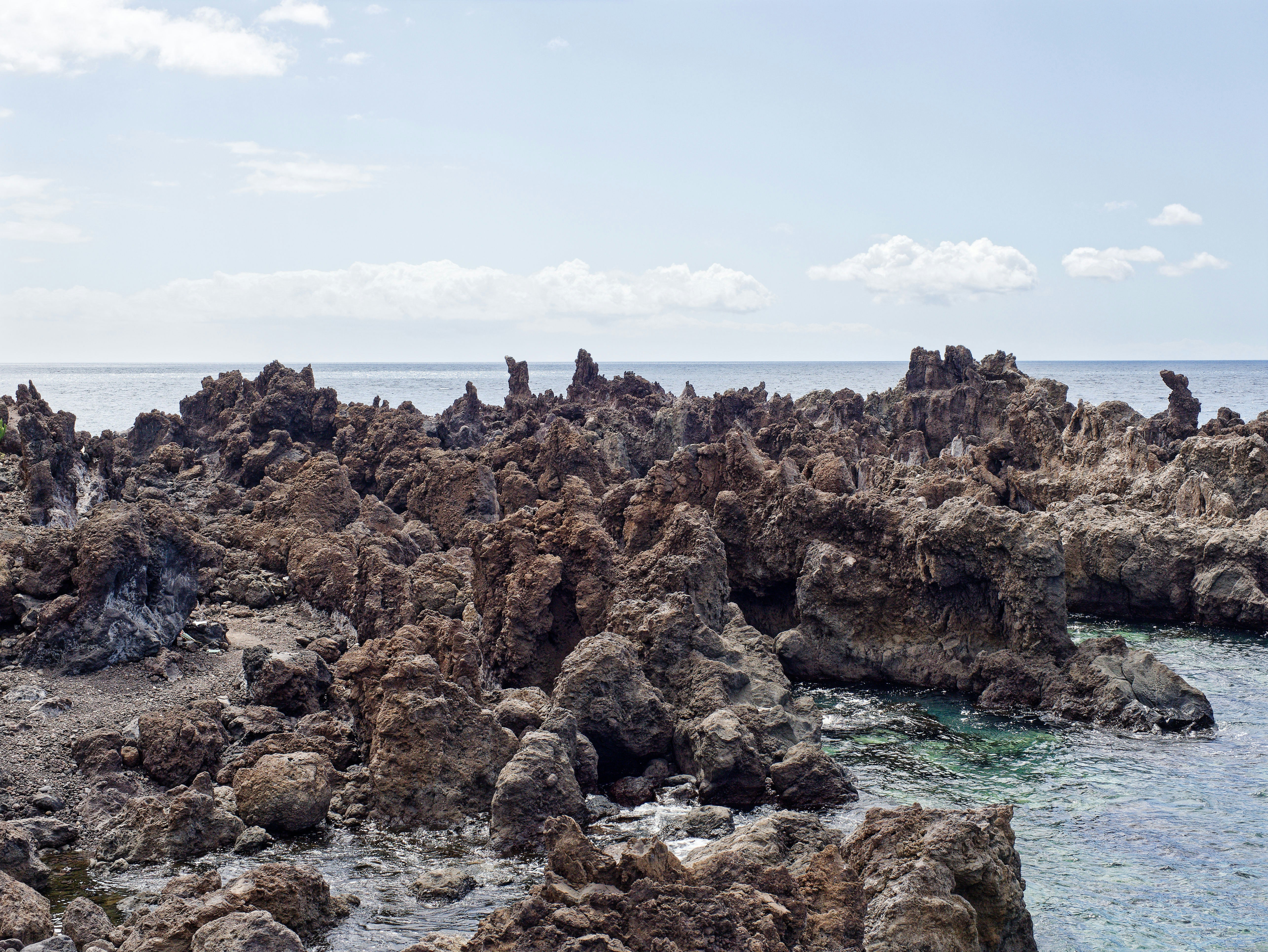 A field of jagged volcanic lava rock meeting calm ocean, the kind the Hoapili Trail crosses