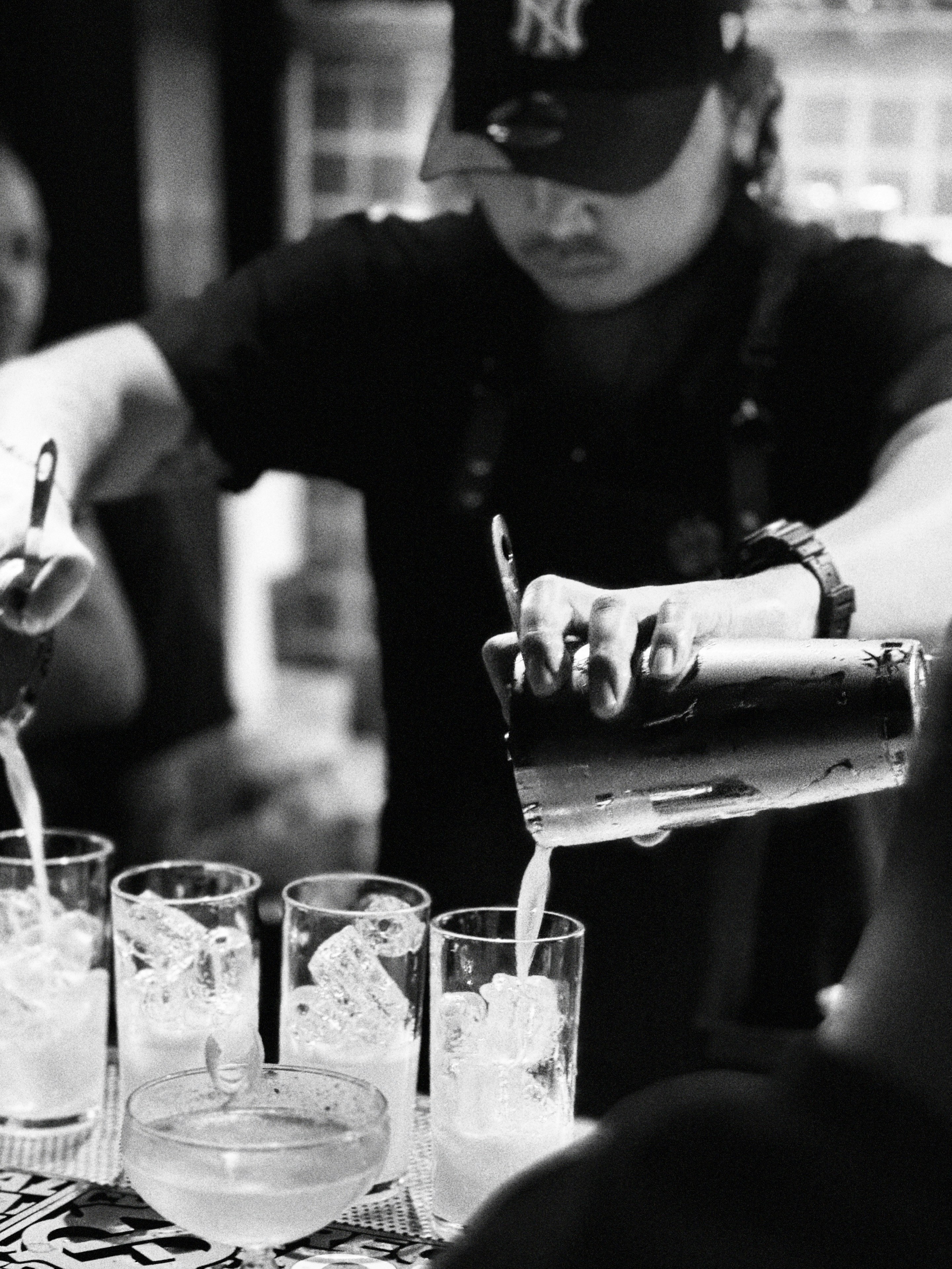 Bartender pouring drink into ice-filled glasses