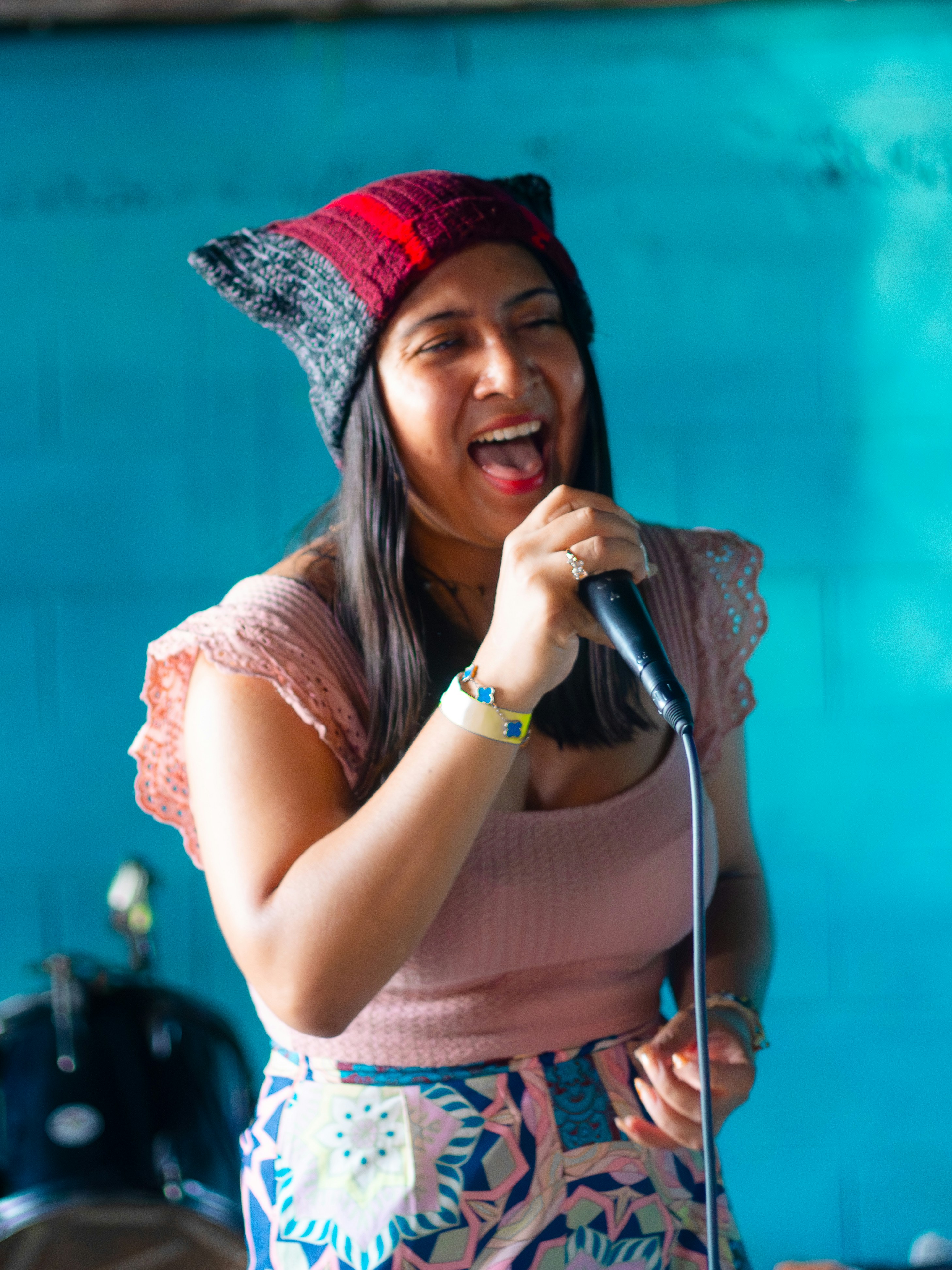 Woman singing into a microphone wearing a beanie.