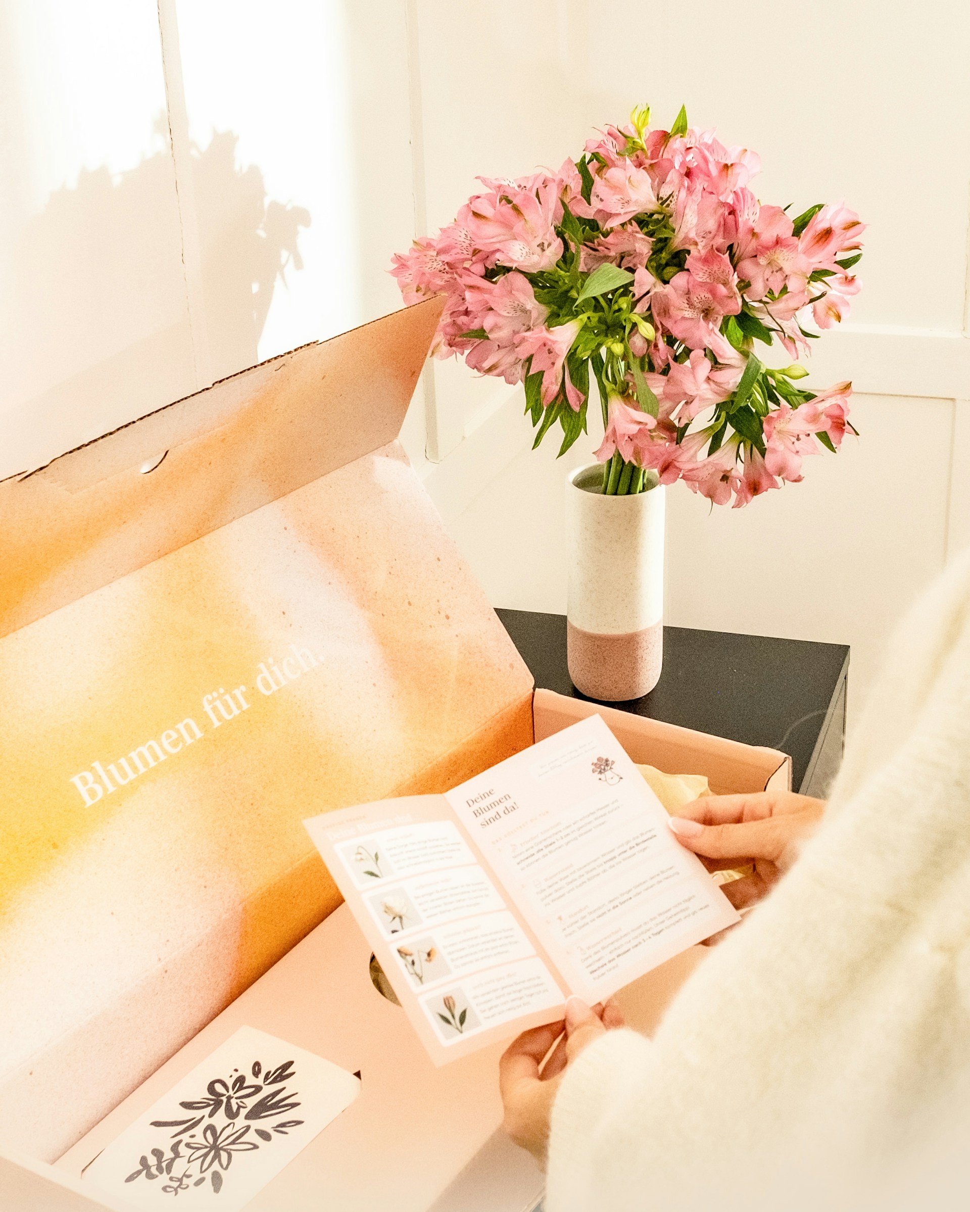 Pink flowers in vase with open delivery box