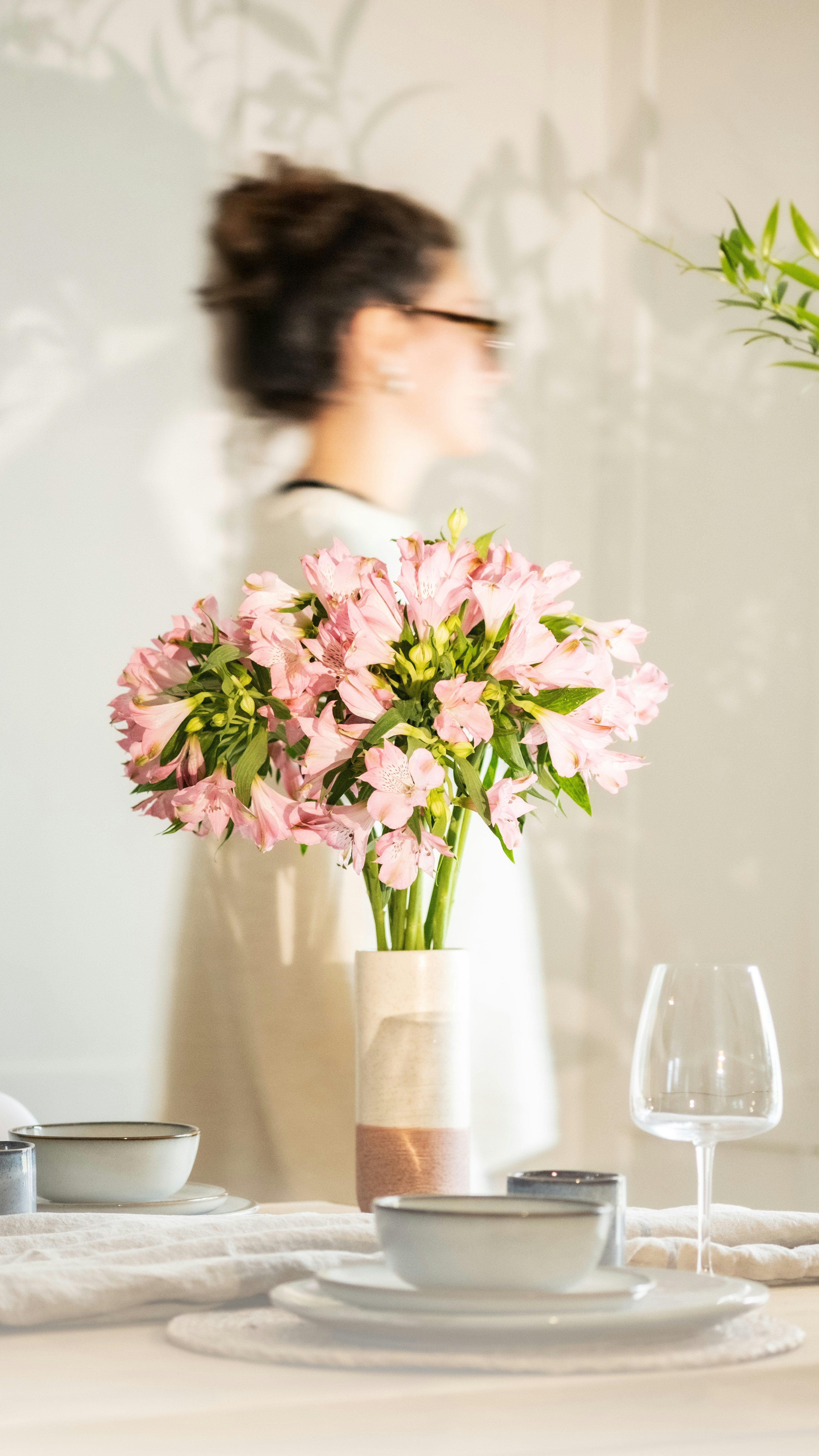 A vase of pink flowers sits on a table setting.