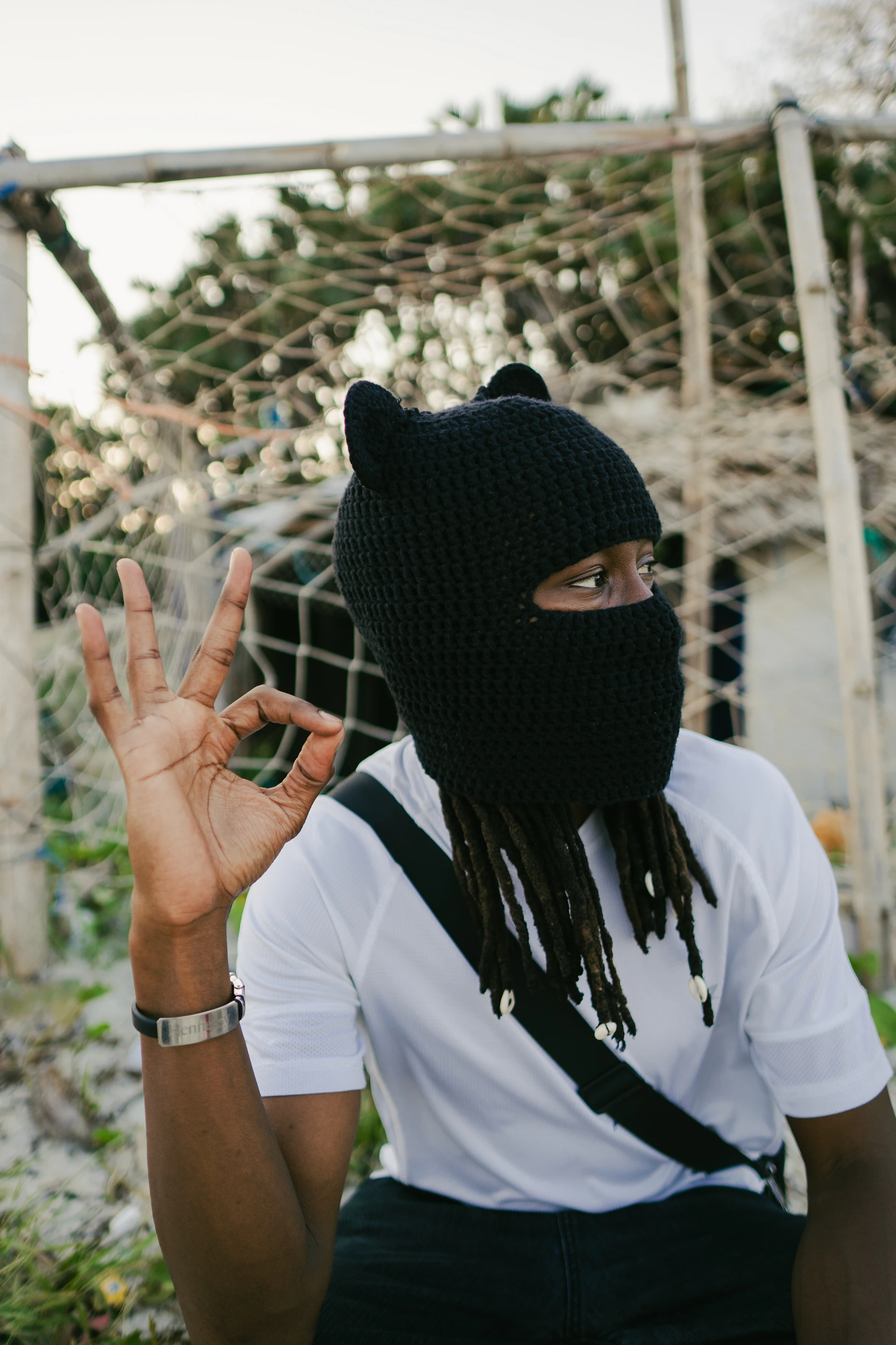 Man wearing black knitted hat with ears, giving okay sign.