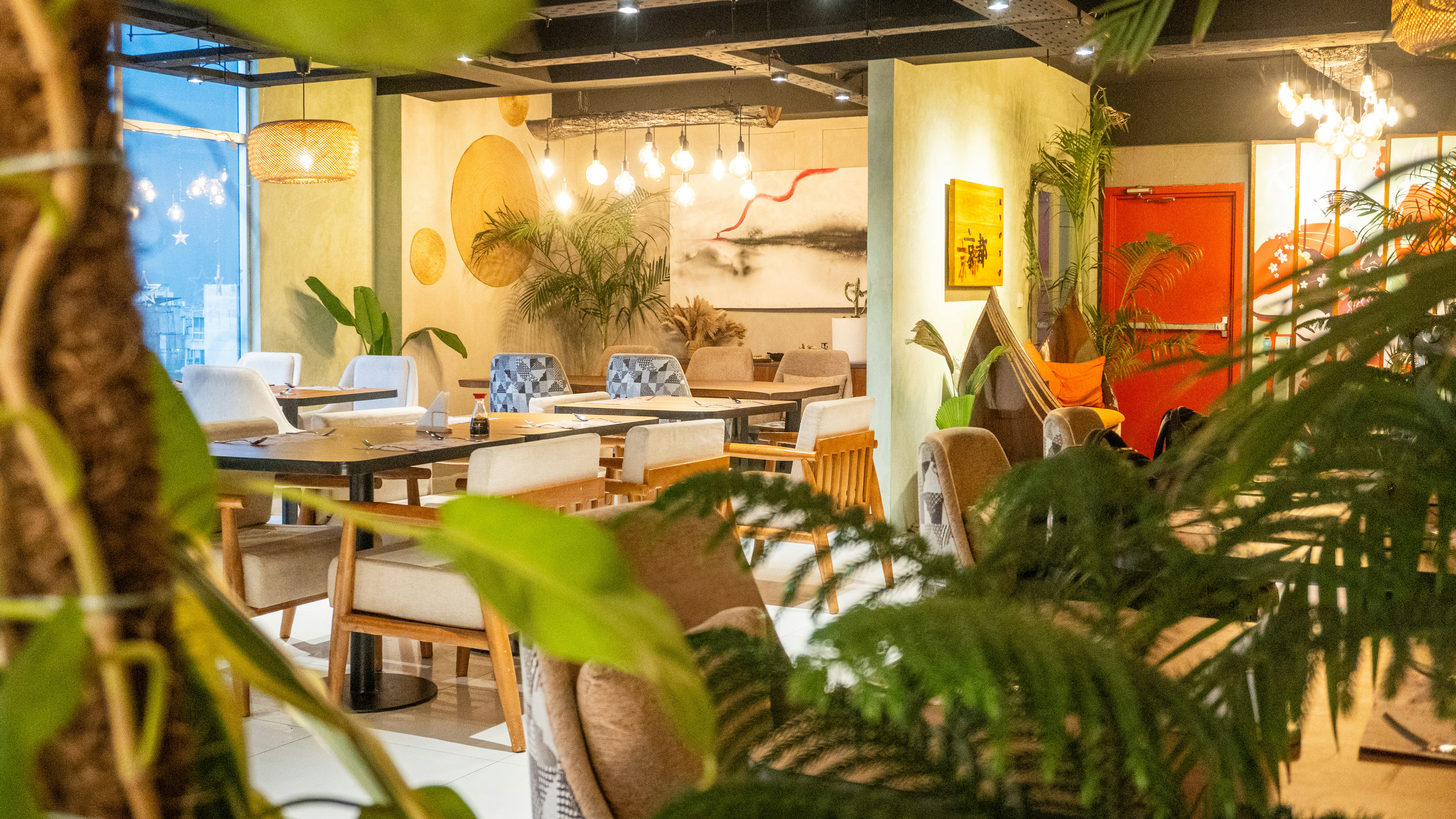 Modern restaurant interior with plants and warm lighting