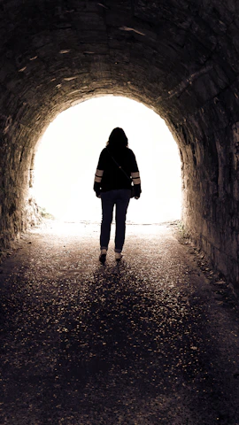 Silhouette of a person walking towards light in a tunnel