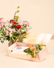 A bouquet of flowers next to an open gift box.