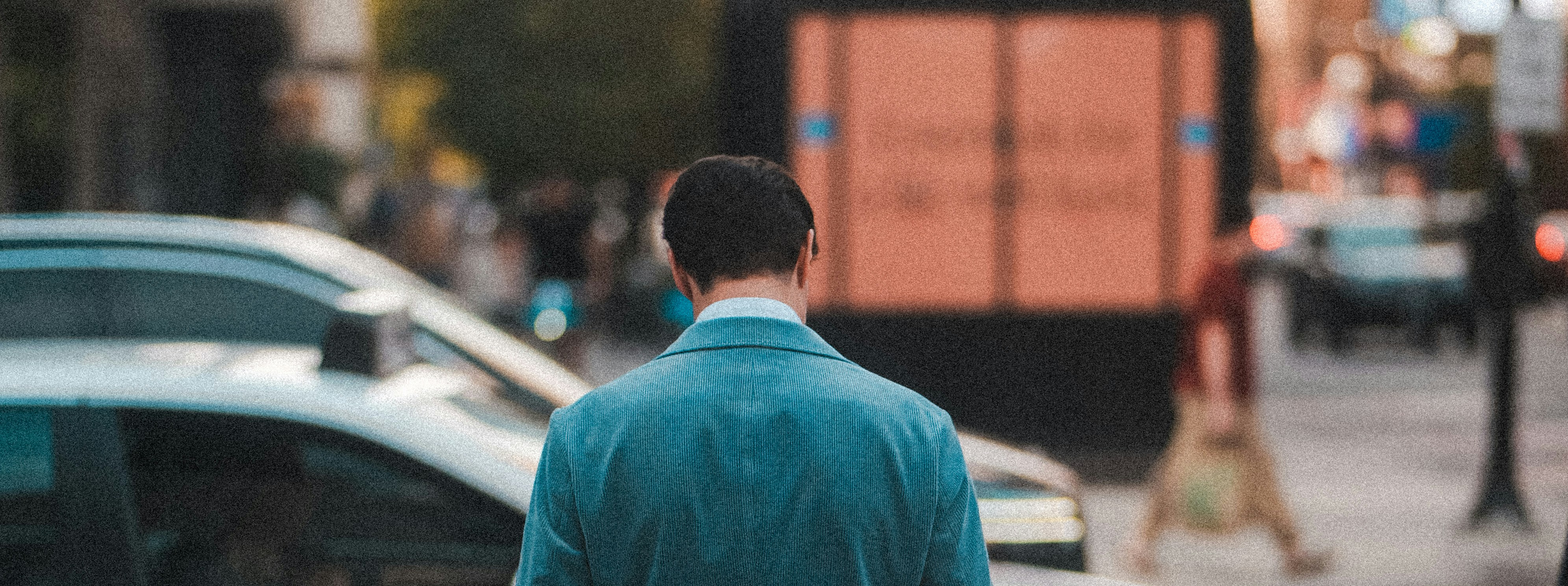 Man in blue jacket walks down a city street.