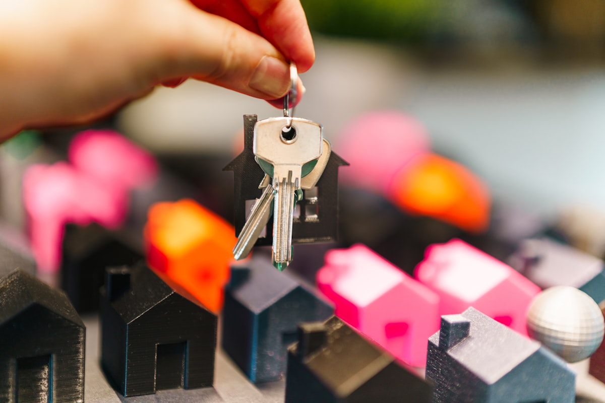 Hand holding house keys over miniature houses representing real estate market