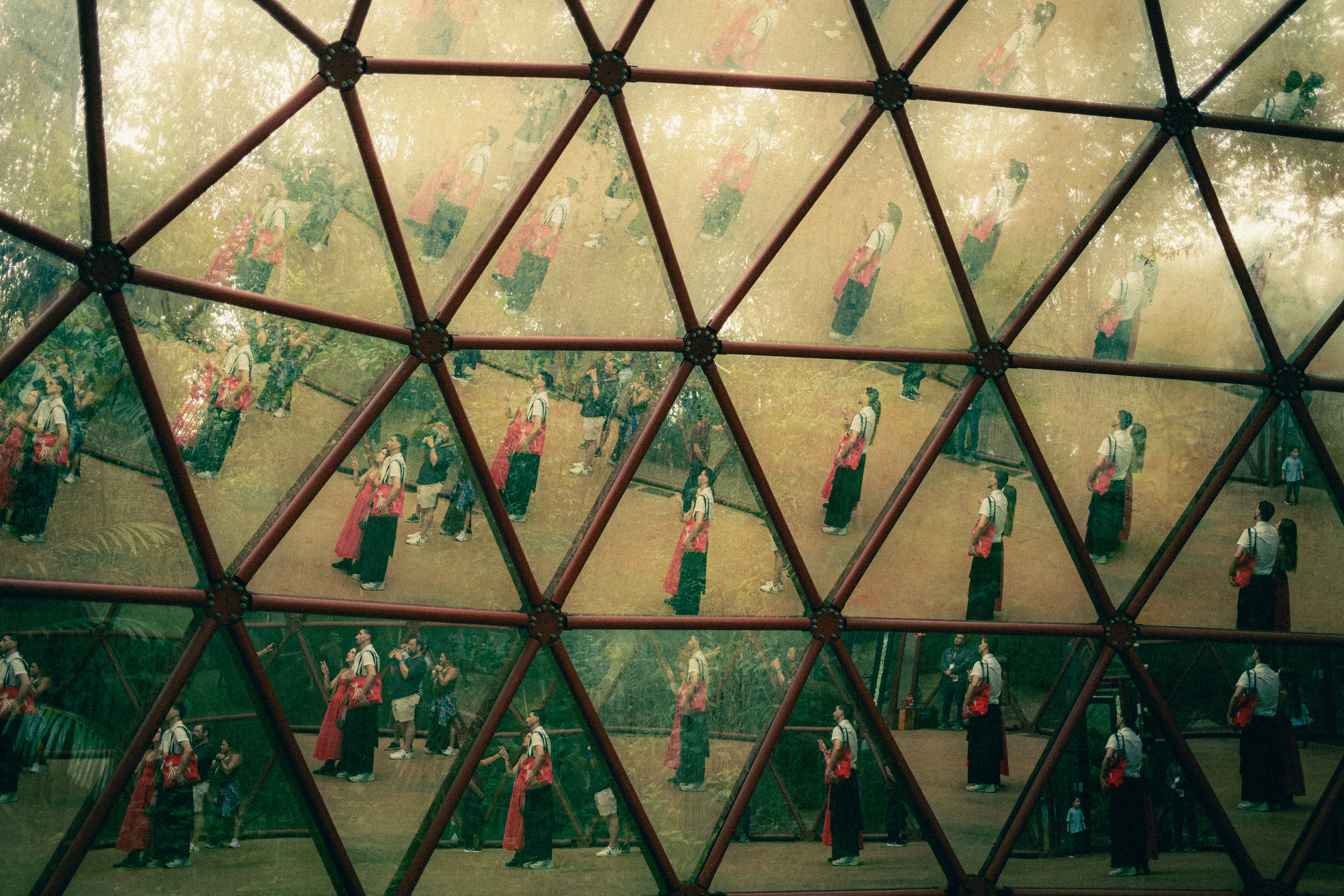 Reflections of people in traditional clothing in geometric dome.