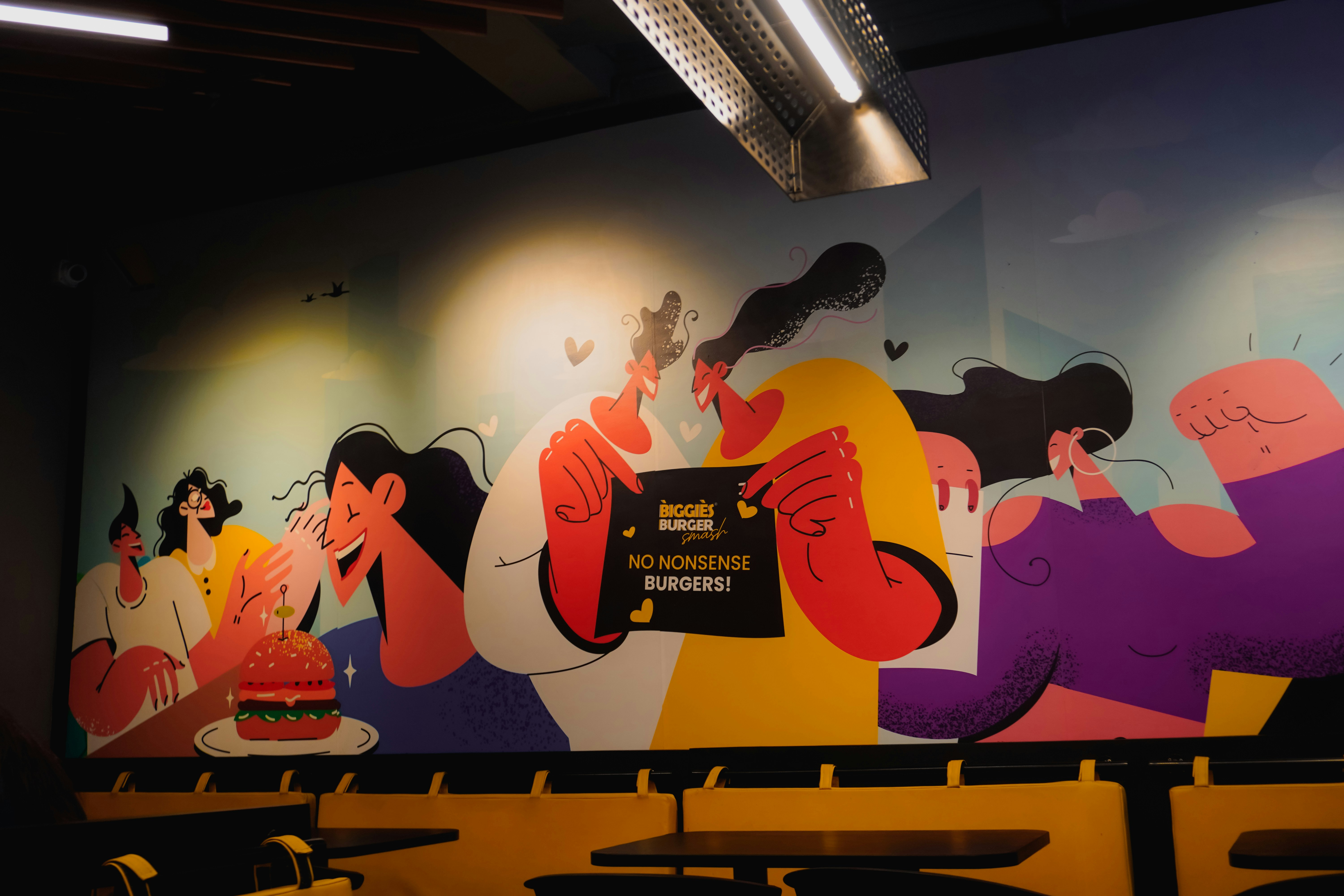 Colorful mural of people enjoying burgers indoors.