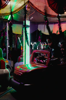 Children ride bumper cars at a carnival at night.