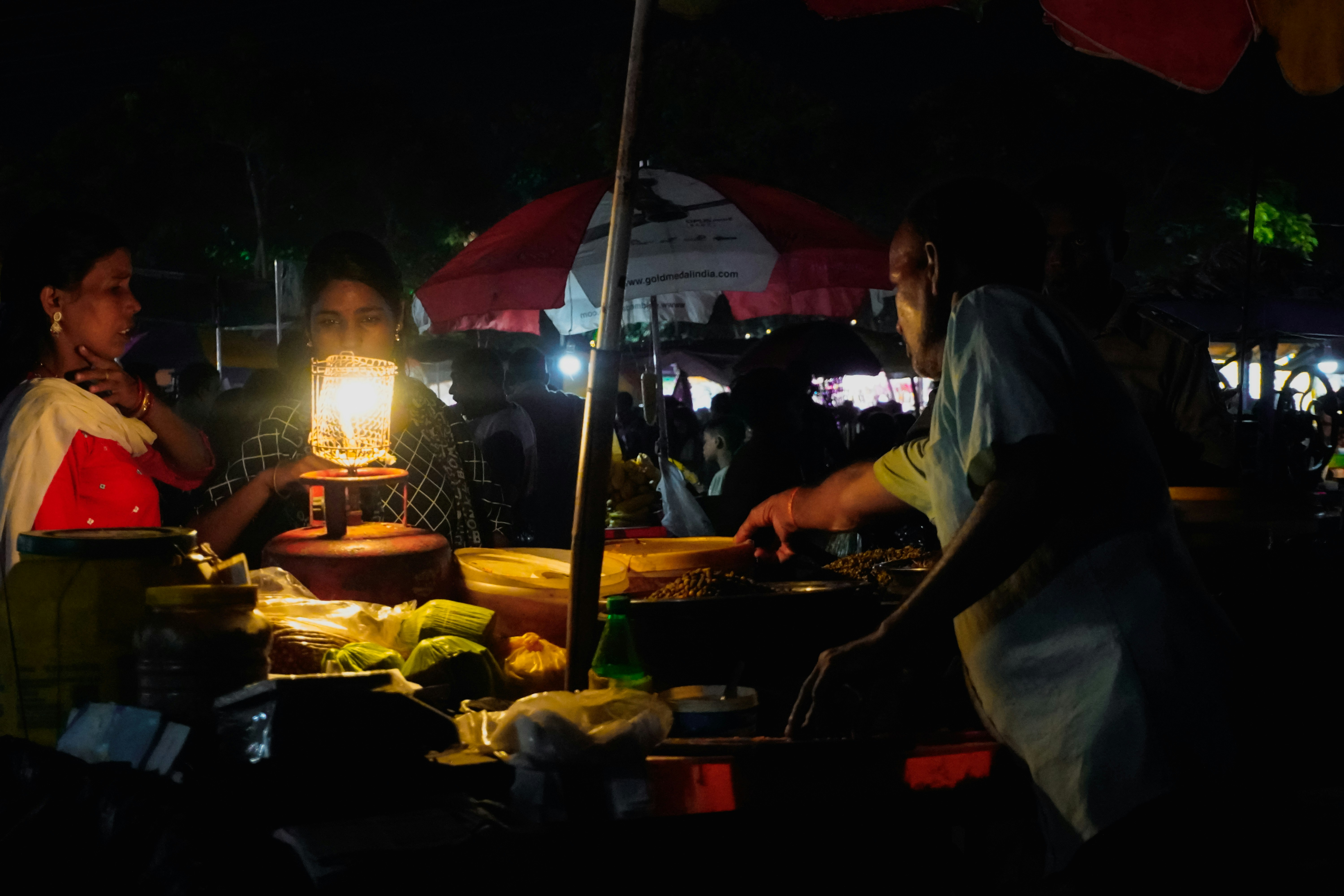 Street vendor preparing food under lantern light at night.
