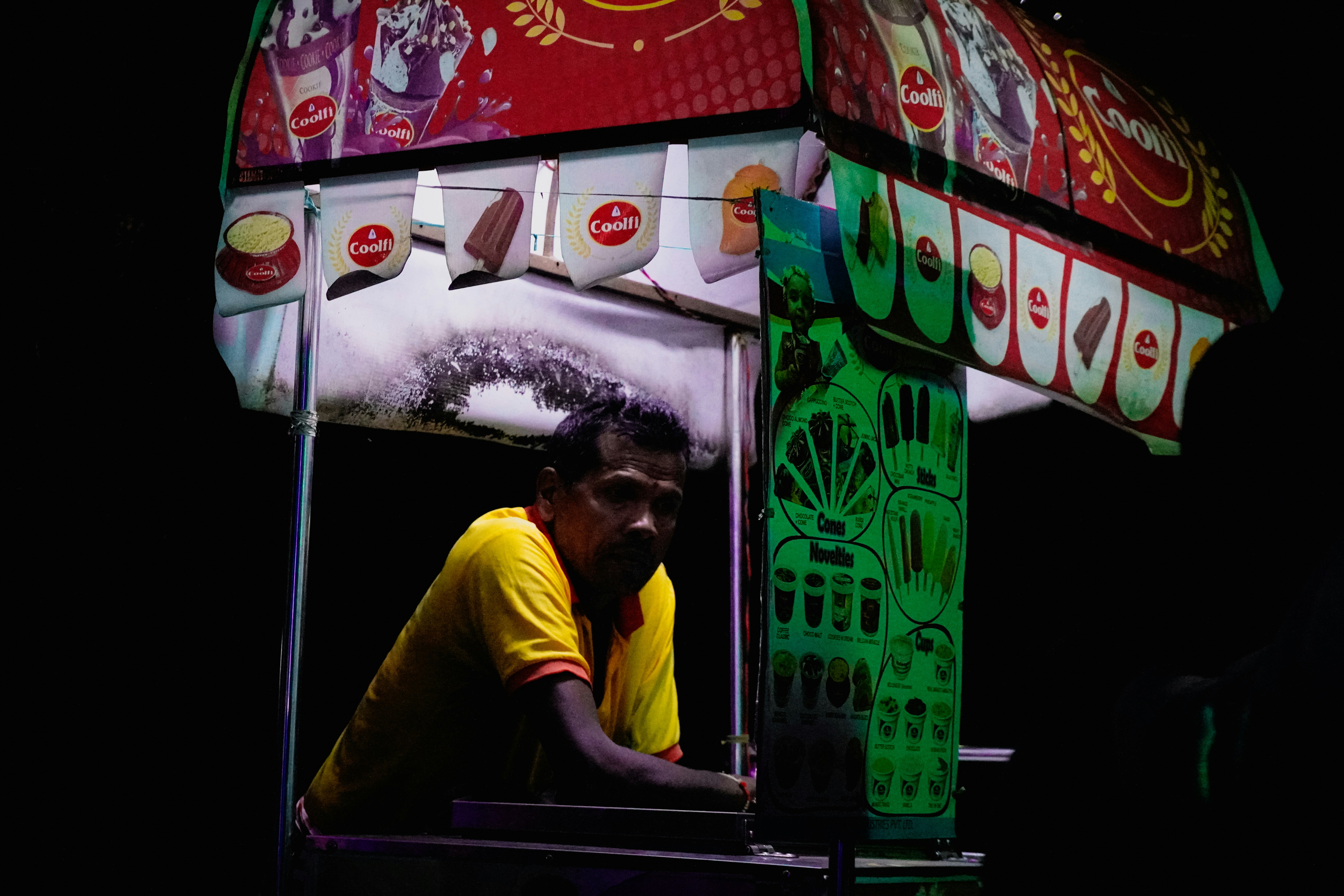 Man working at a colorful night market stall