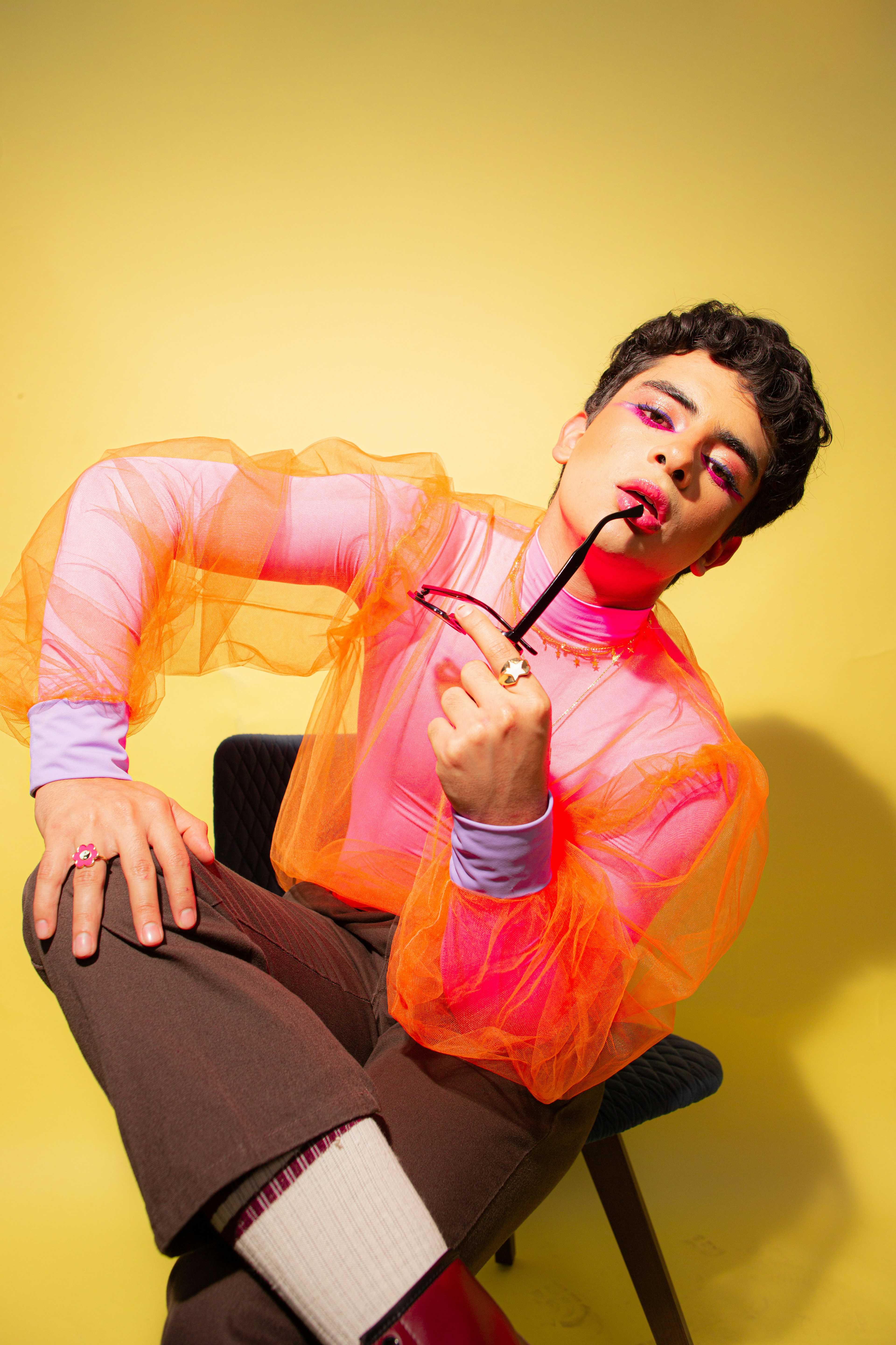 Person in colorful outfit holding glasses to mouth