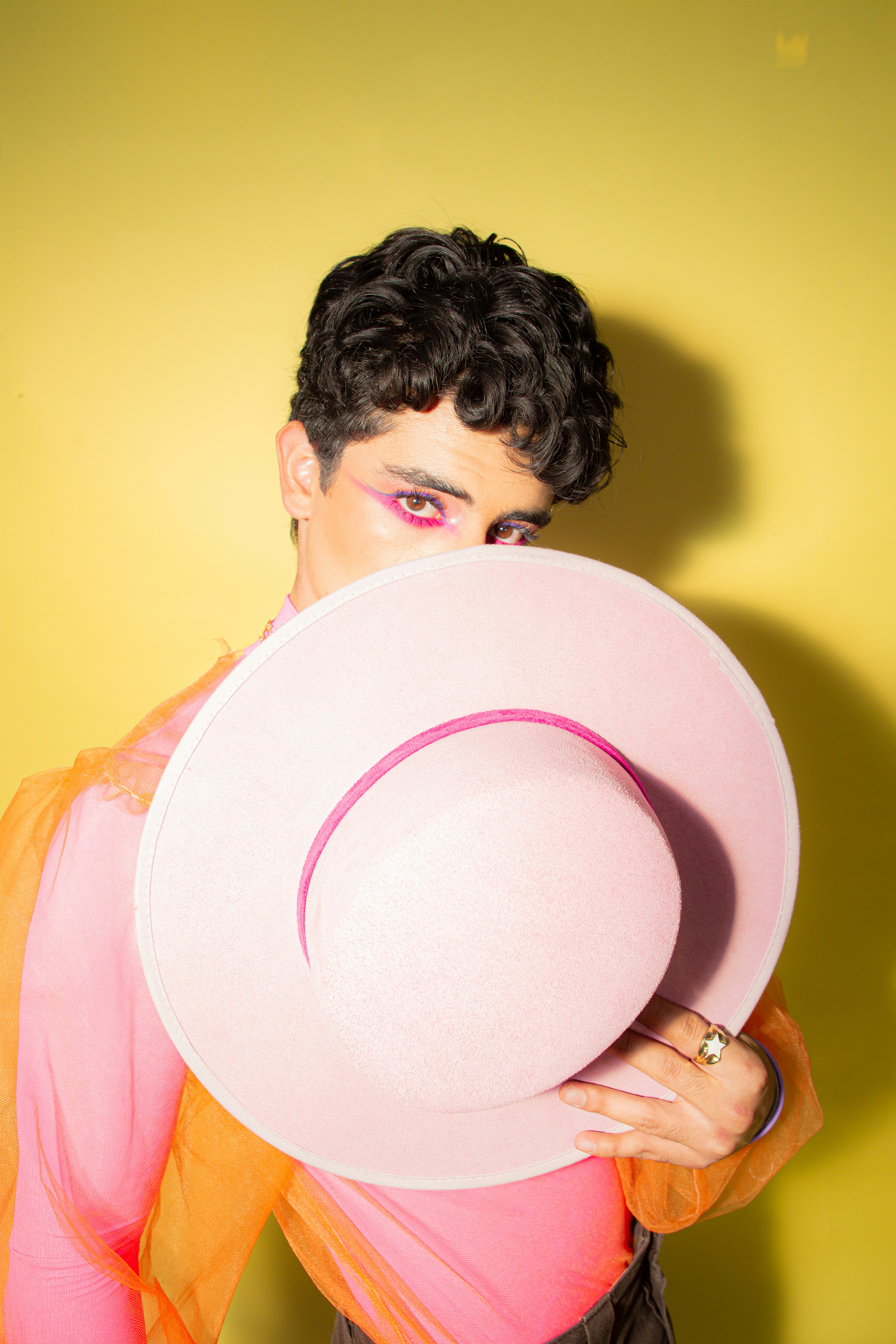 Person with pink hat and bright makeup peeking.